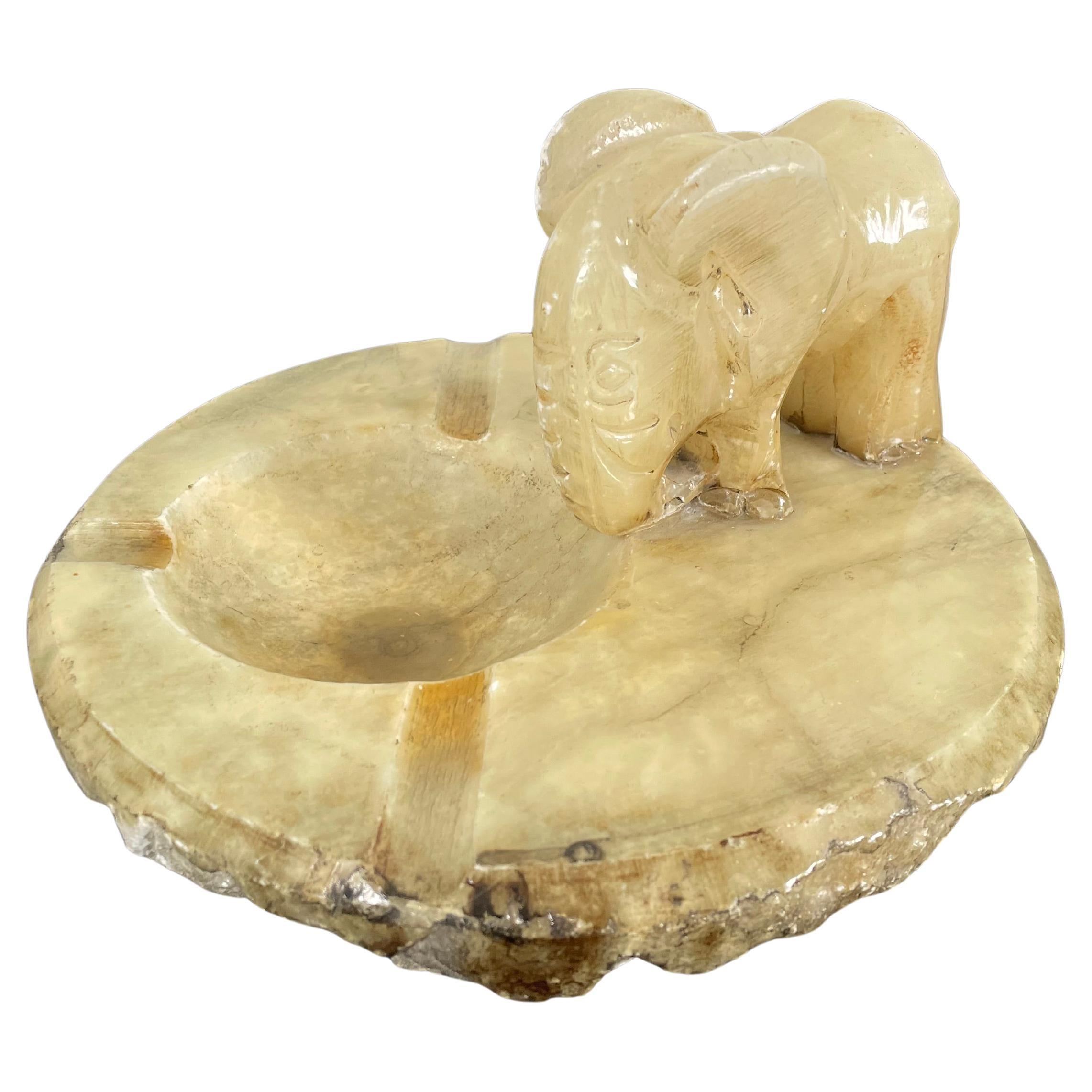 Add a touch of timeless charm to your space with this vintage alabaster ashtray, featuring a beautifully hand-carved elephant motif in an onyx-toned hue. This unique piece effortlessly combines functionality with artistic craftsmanship. The dish is
