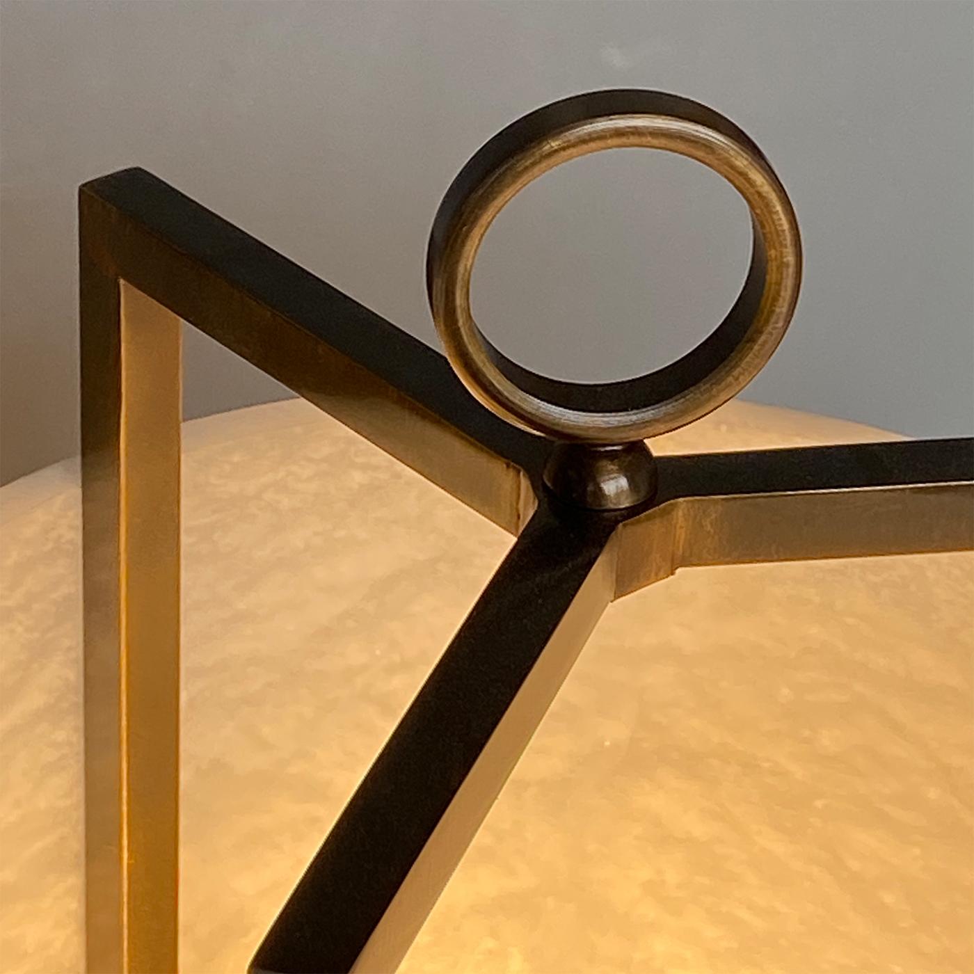 The alabaster Lantern is a table lamp that can easily be placed on the floor. It combines the ethereal allure of the alabaster, evidencing its veining, in contrast with the dark warm effect of the bronze finish. This lamp is composed of a tripodal