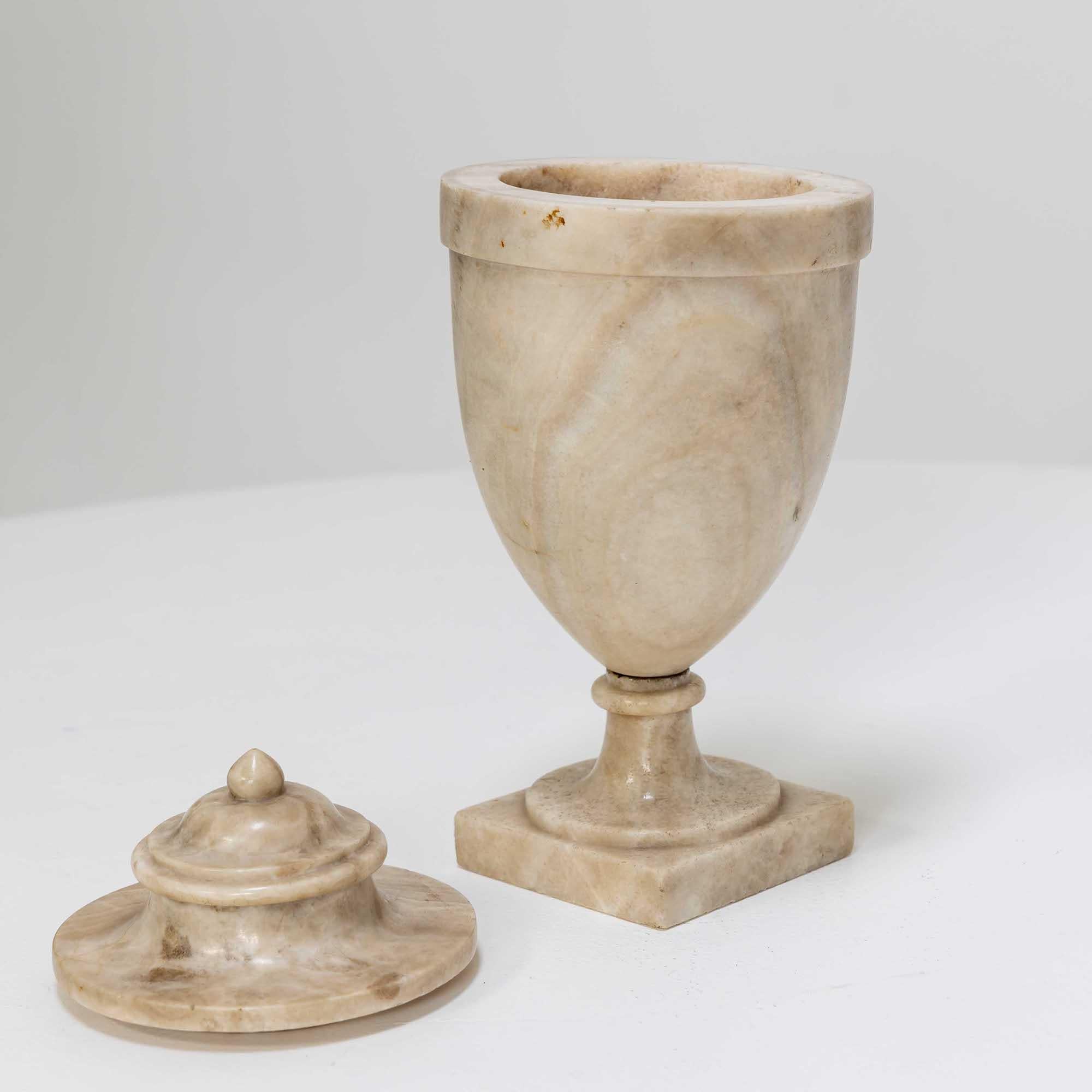 Small lidded urn of alabaster with smooth wall and square base.