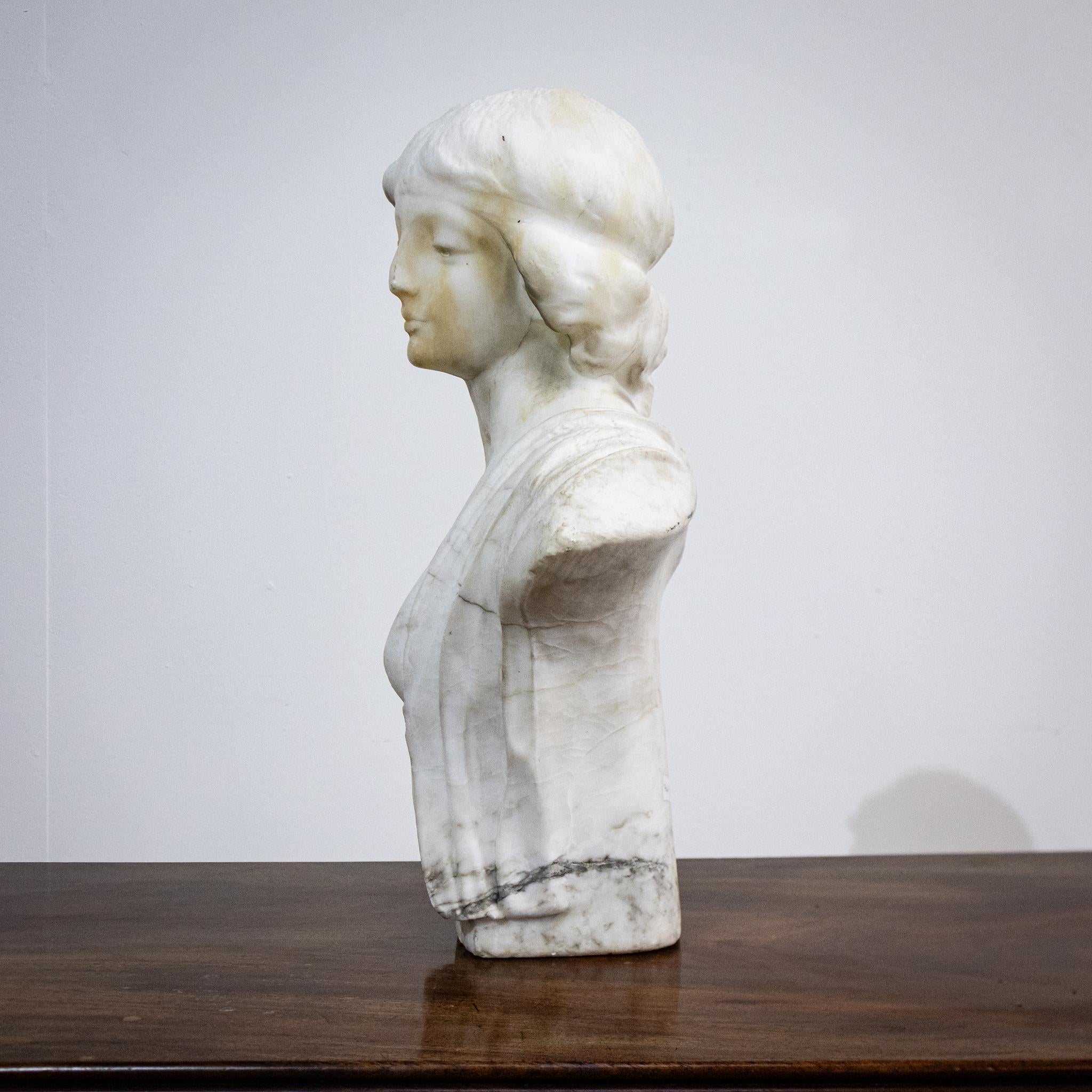 This lovely quality alabaster figure is of a young woman with beautifully sculpted hair, features and clothing folds. The head appears to have been carved separately from the body and there is a joint around the neckline of the dress, although there