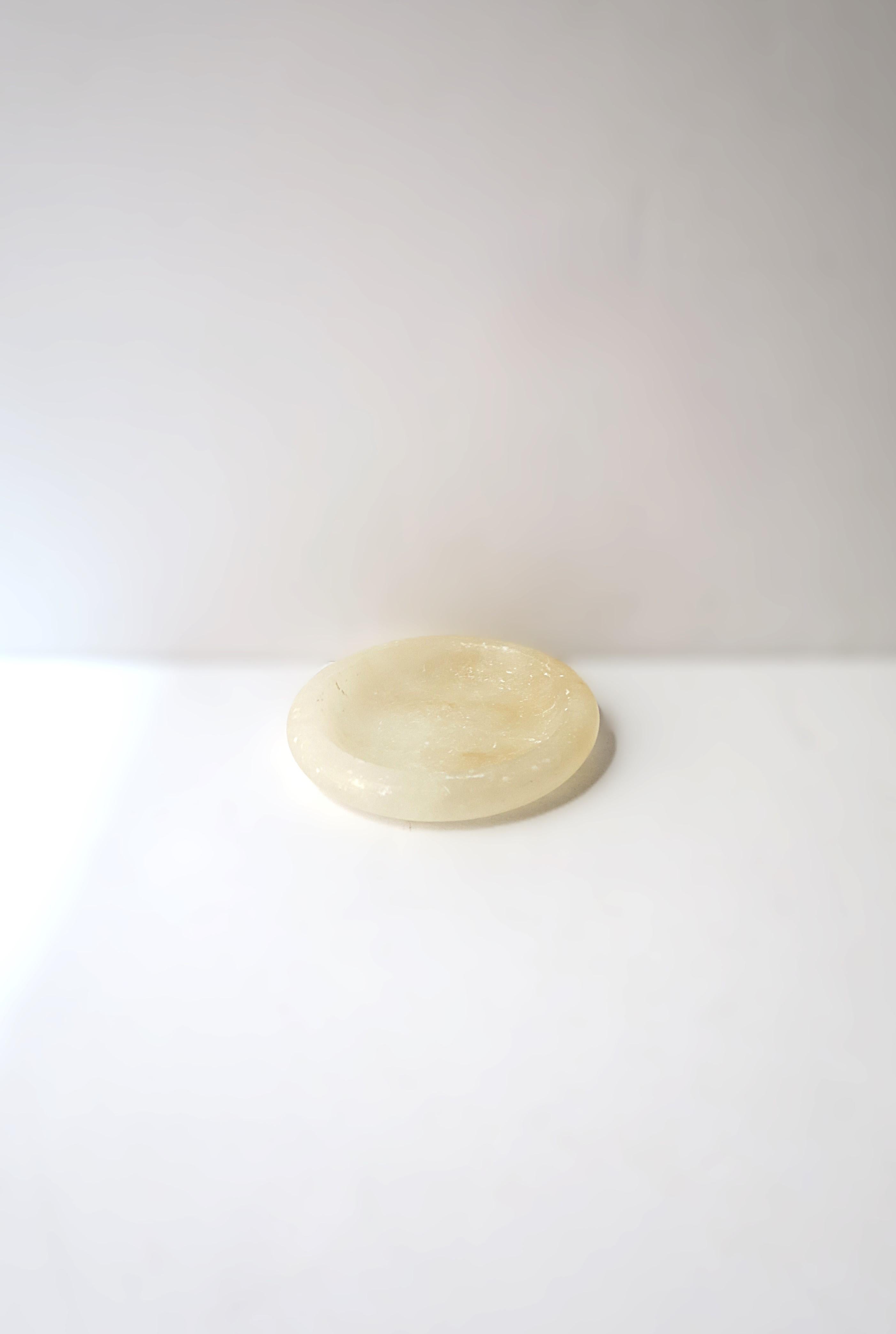 A European alabaster marble jewelry dish, in the Neoclassical style, circa early-20th century, Europe (Italy or Spain.) Dish is round; a great piece to hold small items or jewelry (demonstrated) on a vanity, desk, table, etc. Piece is a translucent