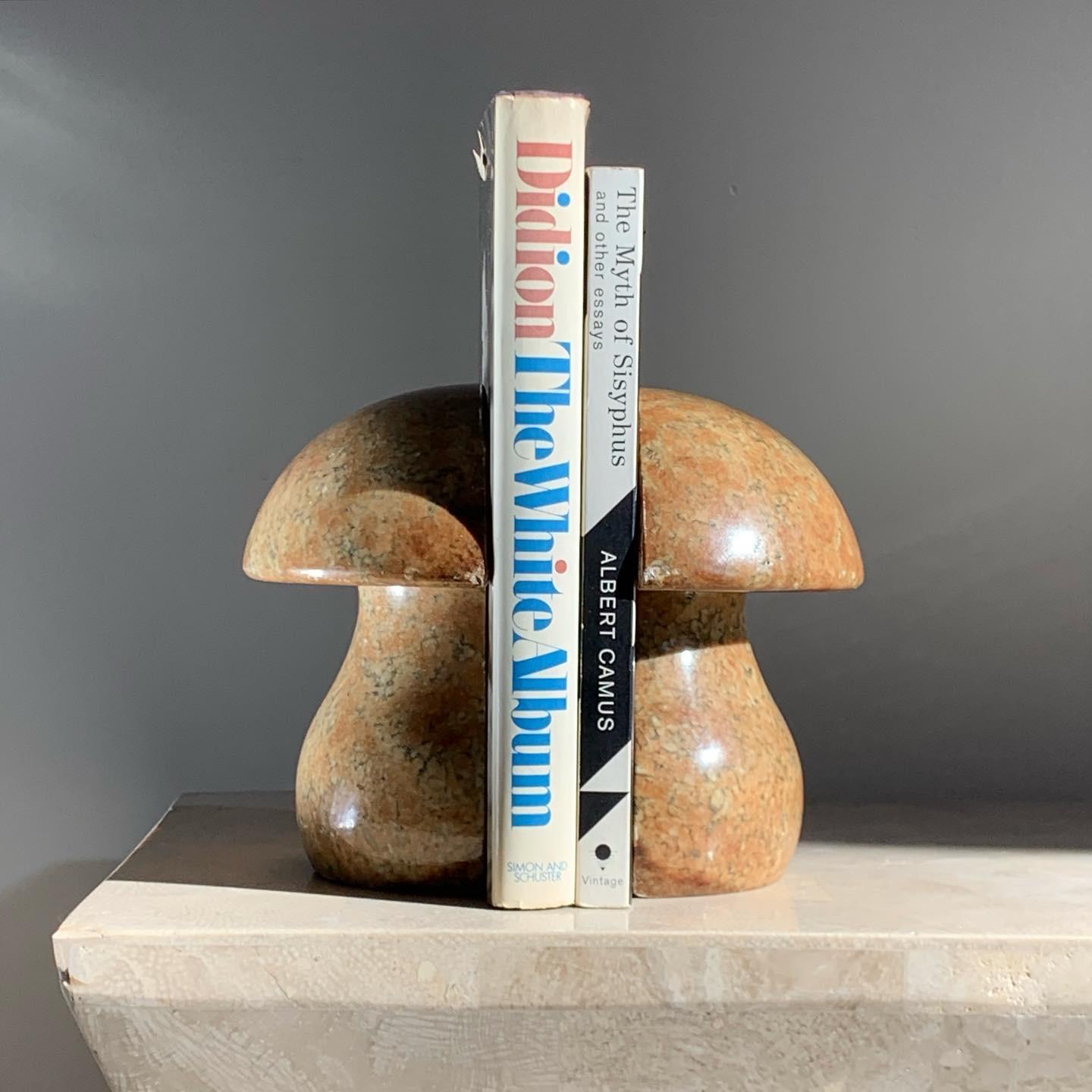 Pair of marble alabaster bookends in the shape of mushroom. Tones of ochre with charcoal and caramel veining. Minor signs of wear; please see pics for the tidbits of wear. Each measures 5.75” W x 2.25” D x 5.75” H.