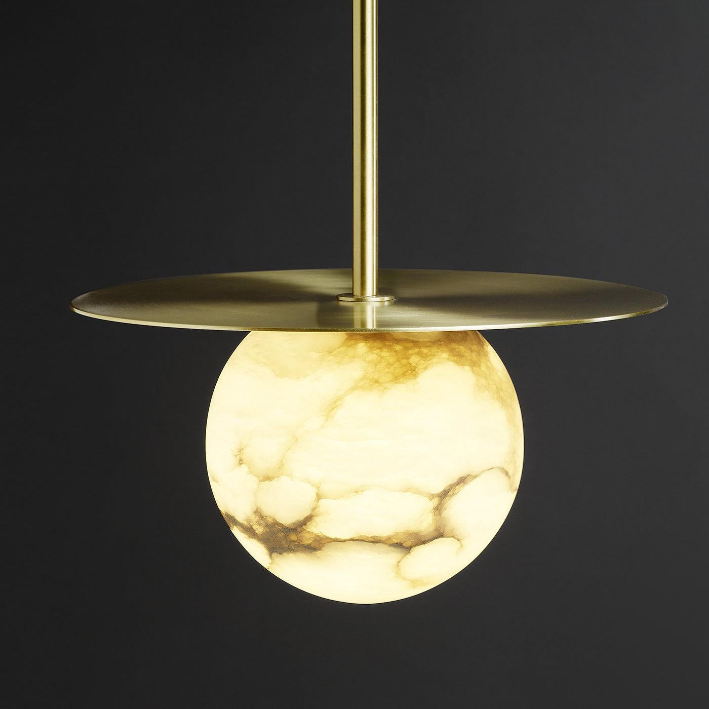 Combinando il fascino etereo dell'alabastro e la calda luminosità dell'ottone satinato, questa lampada a sospensione è un complemento straordinario per un interno raffinato. La luce calda brilla sulle venature uniche della pietra, creando un effetto