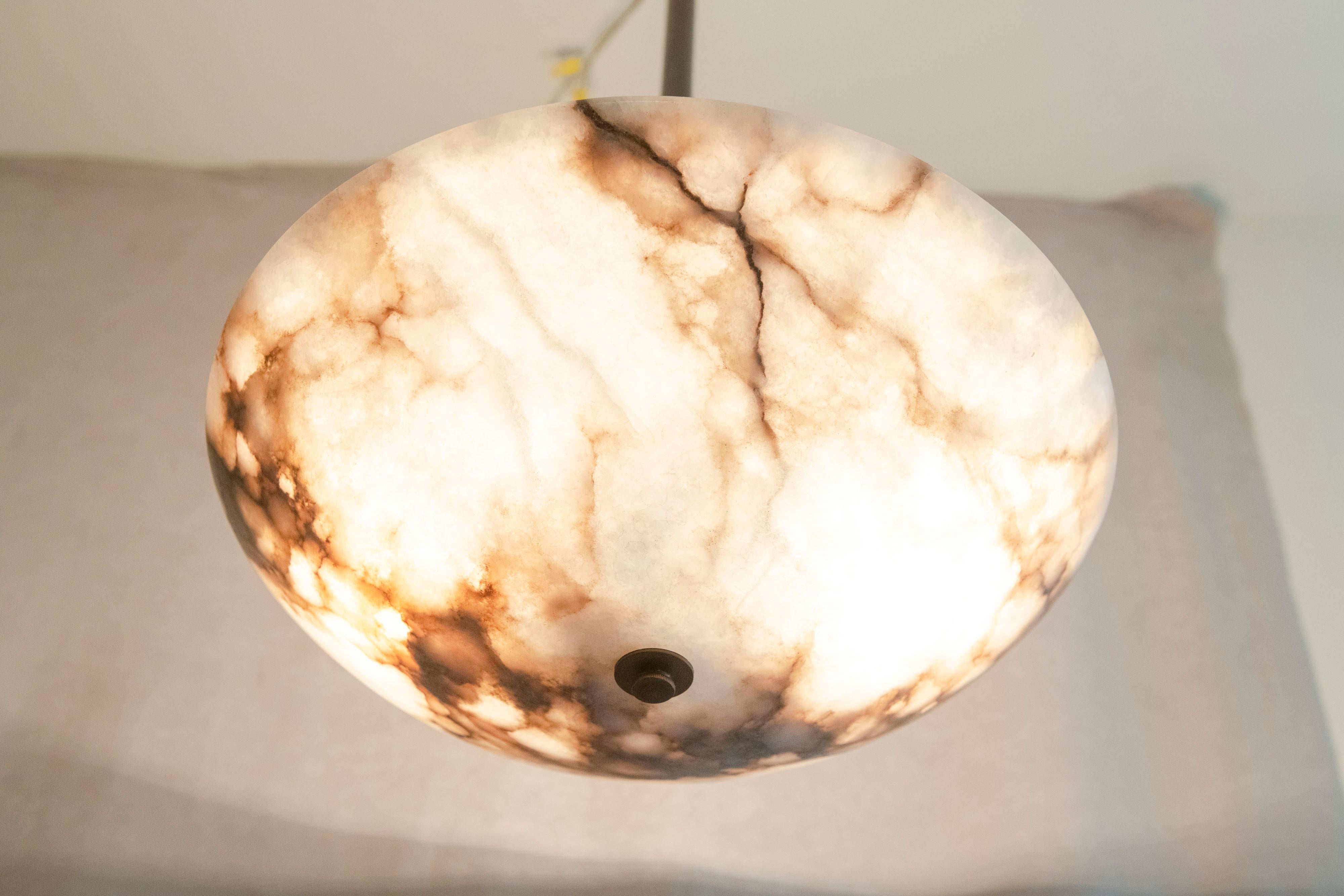 A simple clean alabaster pendant/bowl with very impressive black & white, with a bit dark brown, coloration. A perfect fixture for so many possible rooms.
 Nice simple brass hardware, 2 sockets that light it up as bright or as soft as you wish