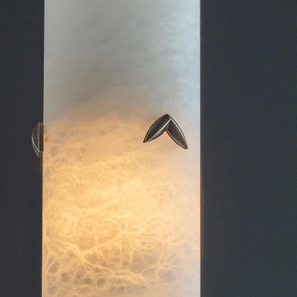 A stunning individual pendant light hewn from solid Alabaster. When lit, the alabaster shade offers a stunning diffuse light and displays a fascinating marbled texture. Each Alabaster pendant light shade is presented with three bronze leaf details.
