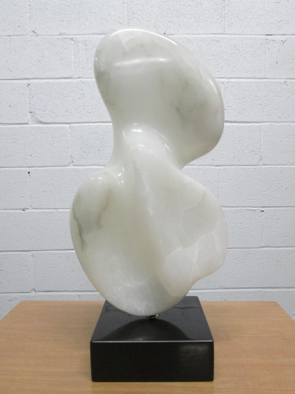 Organic form alabaster sculpture on a stone base which allows the sculpture to rotate easily.
