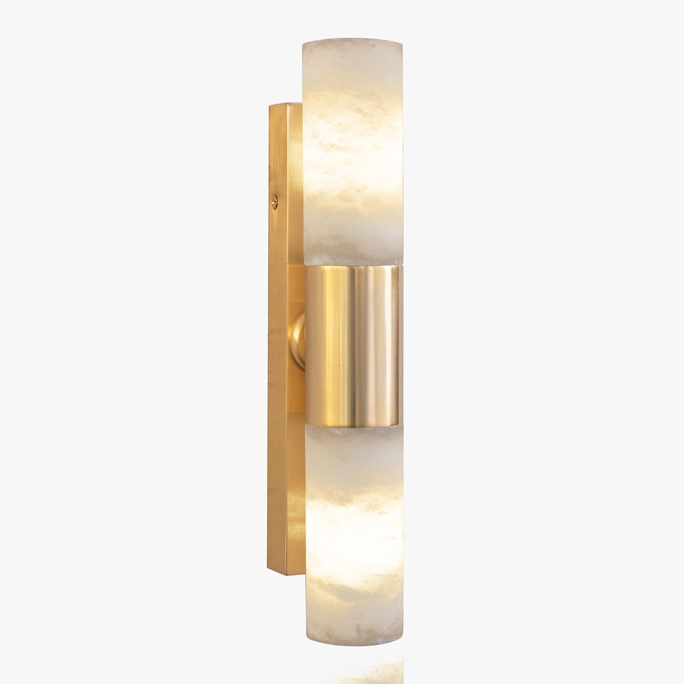 Il calore dell'oro incontra la purezza dell'alabastro in questa elegante applique a due luci di ispirazione minimalista. Linee pulite tracciano l'intera silhouette, dalla struttura in ottone placcato oro satinato ai due paralumi cilindrici in