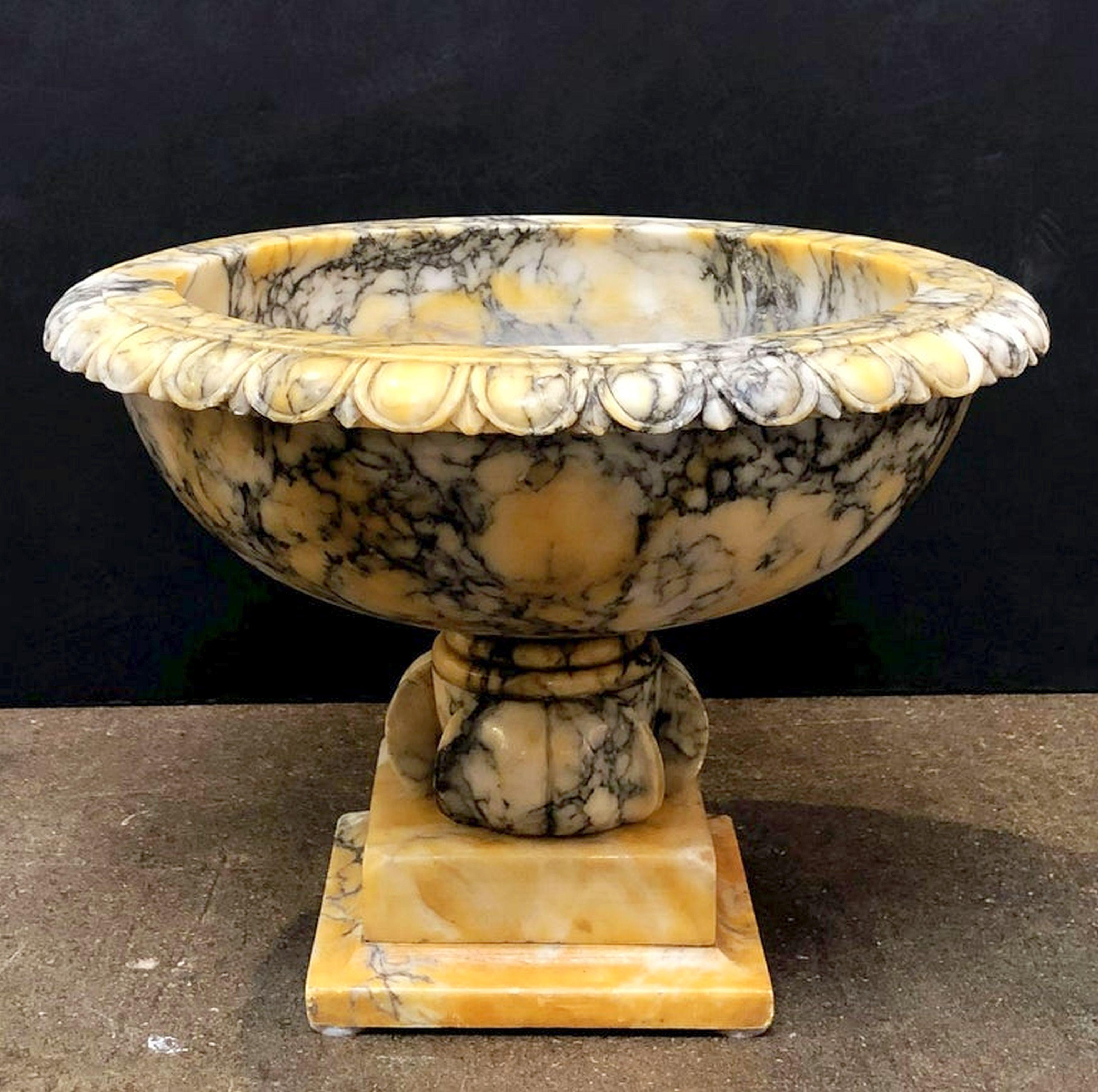 A fine urn or pot of alabaster in the Classical style from Italy, featuring an egg-and-dart rolled edge, over a circular bowl-shaped body, set upon a raised square plinth.