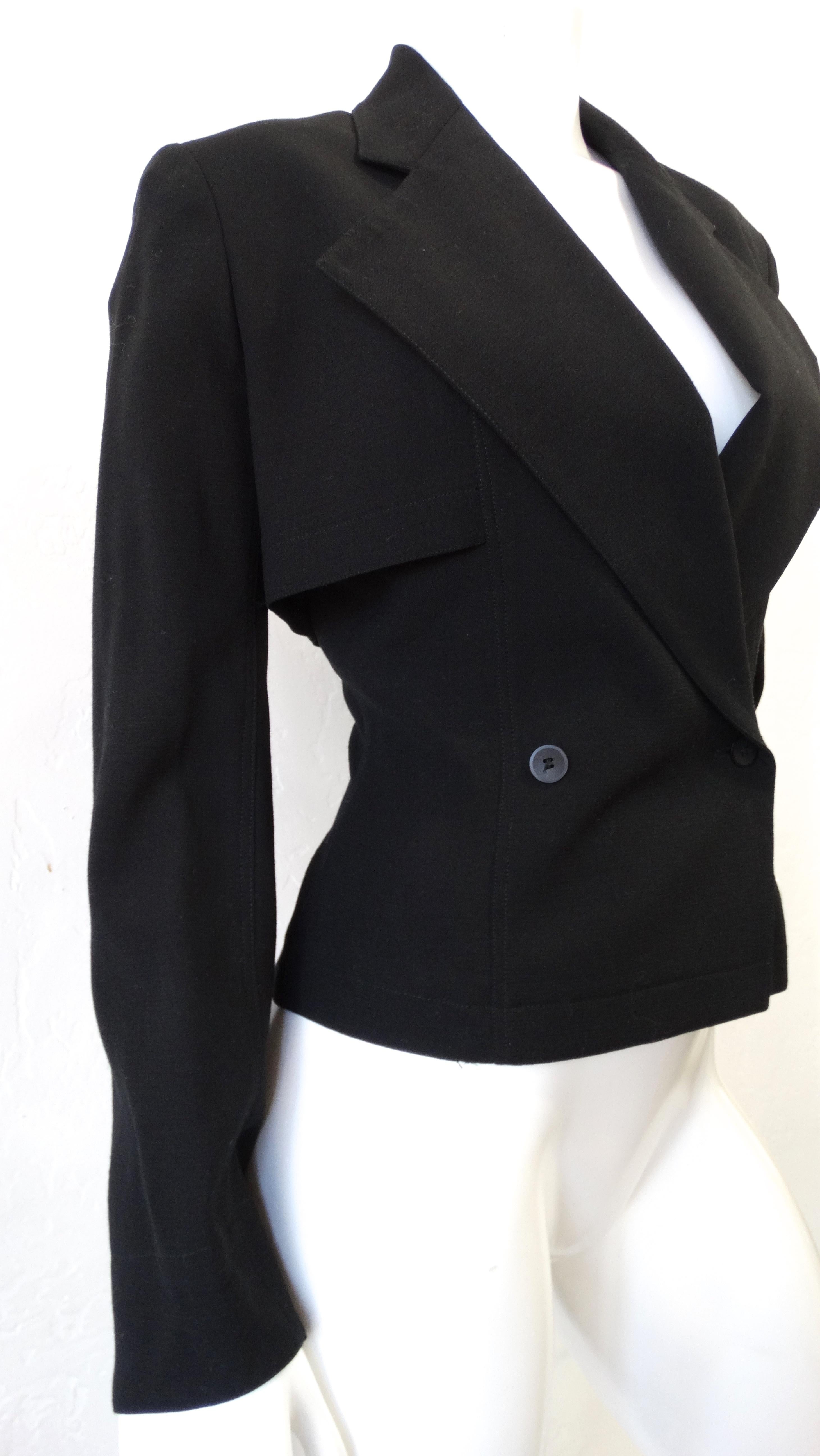 Elevate your look with this amazing Alaia blazer! Circa 1980s, this black double breasted blazer is crafted from 100% Wool and features long sleeves with slits at the cuff and a large notched collar with a cropped section of fabric around the back.