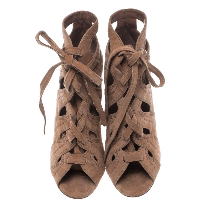 Alaia brings to you these fabulous booties to make a statement every time you step out in them. The beige booties are crafted from suede and feature a peep-toe silhouette. They flaunt an artistic cut out design and lace-ups that run through the