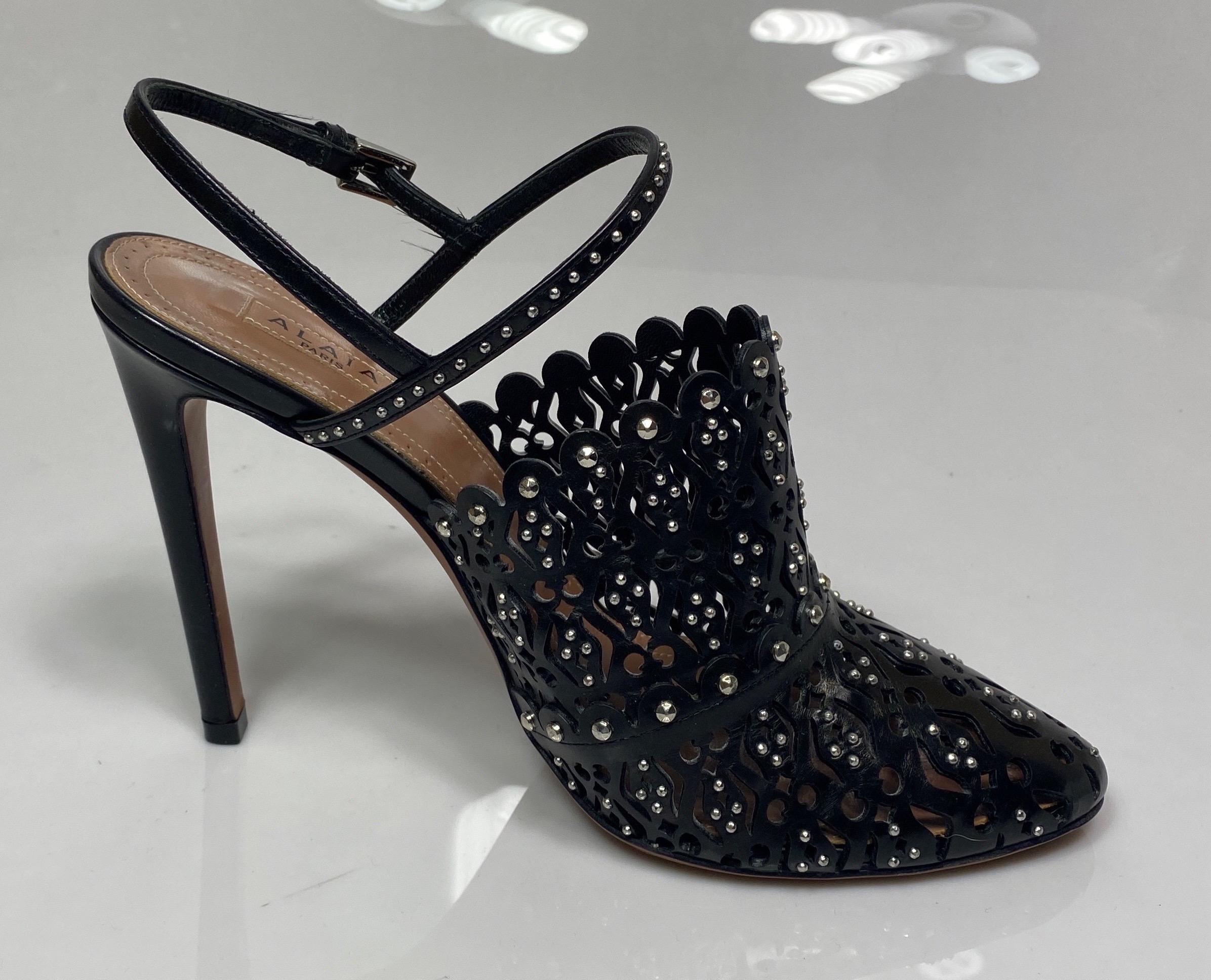Alaia Black “Bottines” slingback heels - Size 37.5. The description is:
4.5” heel height
Double strap with adjustable buckle
Perforated leather looking like lace
Multi size silver metal studs throughout
Comes with shoe box
Excellent condition