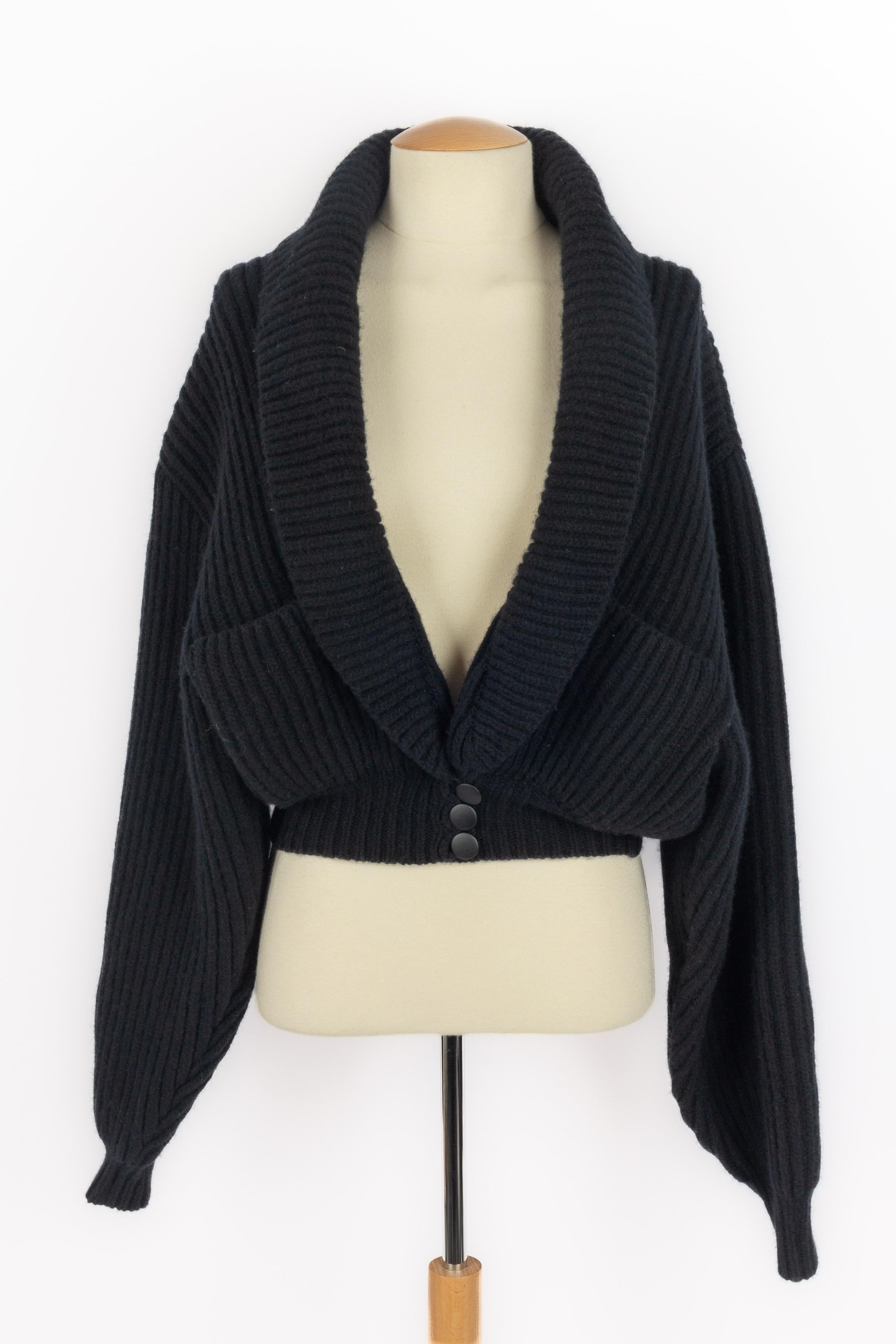 ALAÏA - (Made in Italy) Cárdigan corto de lana negra con mangas largas. Talla 38FR indicada.

Estado:
Muy buen estado

Dimensiones:
Anchura de los hombros: 57 cm - Pecho: 50 cm - Longitud de las mangas: 66 cm - Largo: 53 cm

SKU:FV123


