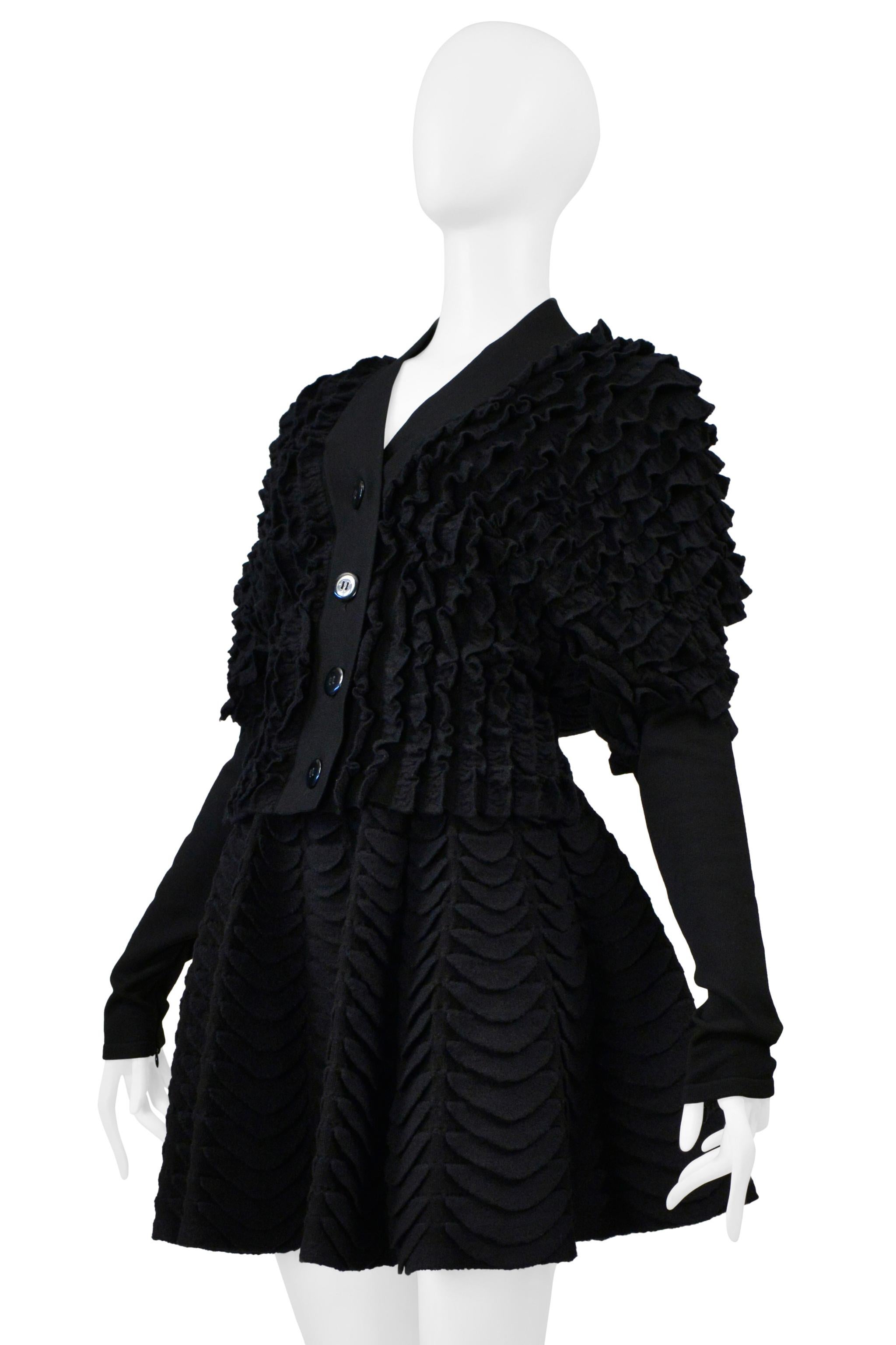 Resurrection Vintage è entusiasta di offrire un set di cardigan e gonna a ruota in maglia di Alaia. Il cardigan è caratterizzato da una chiusura frontale a quattro bottoni, maniche in maglia a coste e vestibilità aderente. La gonna ha una silhouette