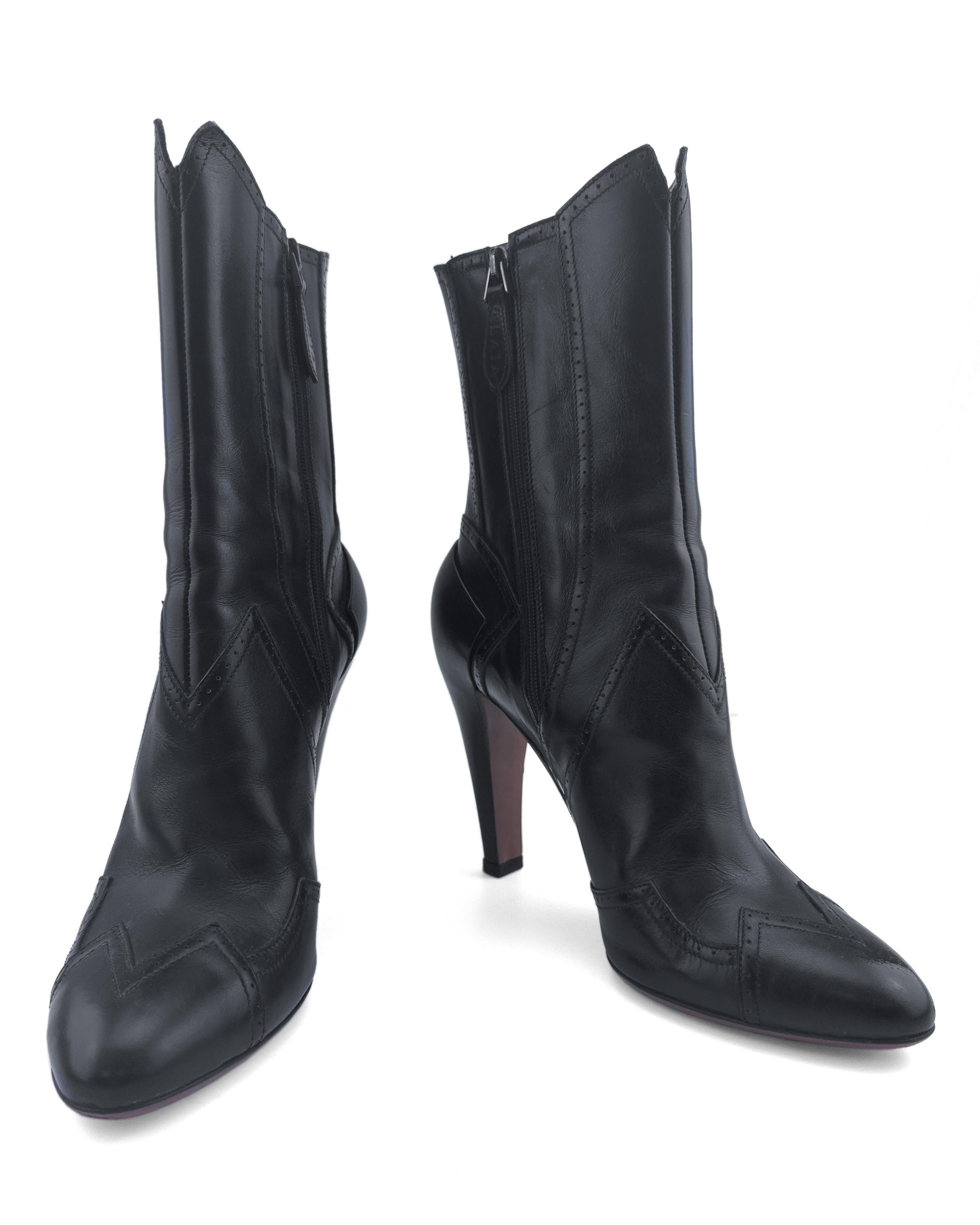 Logrando un equilibrio perfecto entre feminidad refinada y fuerza arquitectónica, estas botas a media pantorrilla de piel negra de Alaïa reinterpretan los motivos clásicos del oeste a través de la lente parisina característica de la maison. Cortadas