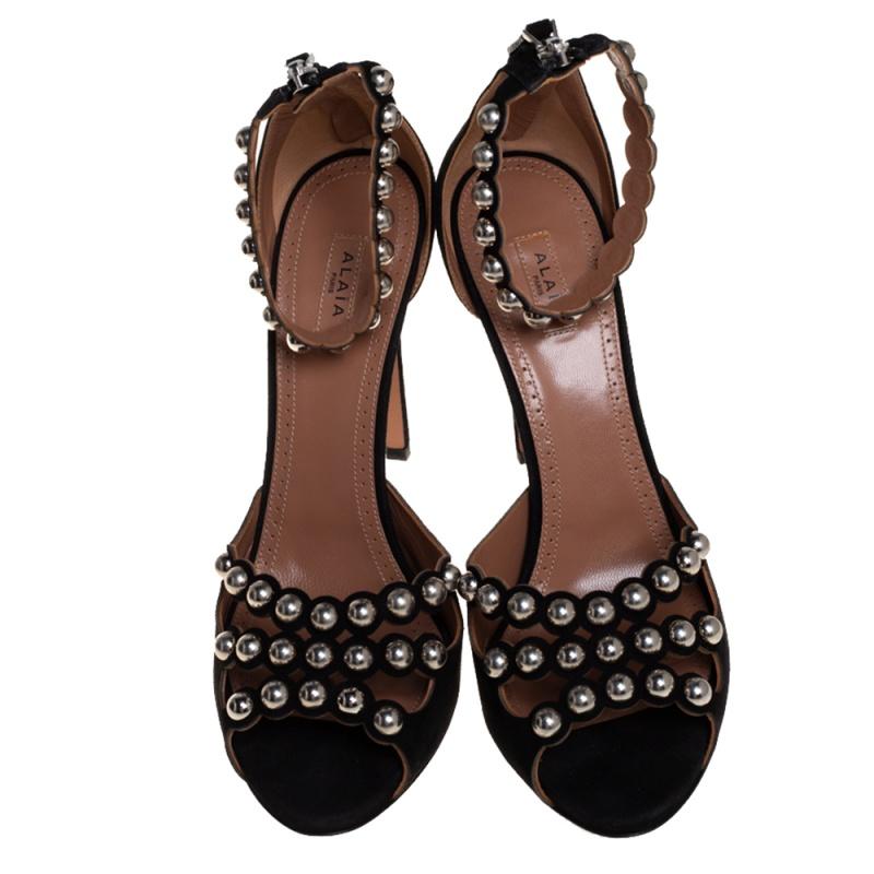 Artistically designed to adorn your feet with sheer elegance, these Alaia sandals are a must-buy! The black sandals are crafted from suede and feature an open-toe silhouette. They flaunt studded vamp straps and ankle straps and come equipped with