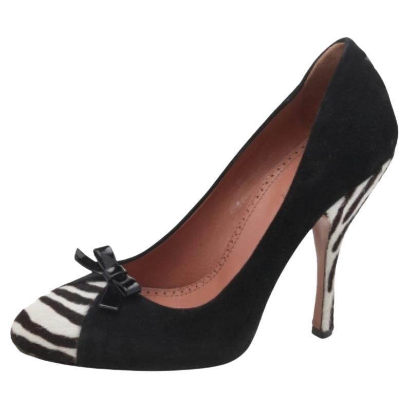 Cette paire d'escarpins en daim est idéale pour être associée à la tenue de votre choix. Cette paire d'escarpins de la maison Alaia est extrêmement polyvalente avec ses bouts ronds, son empeigne ornée d'un nœud et ses talons hauts. Les panneaux en