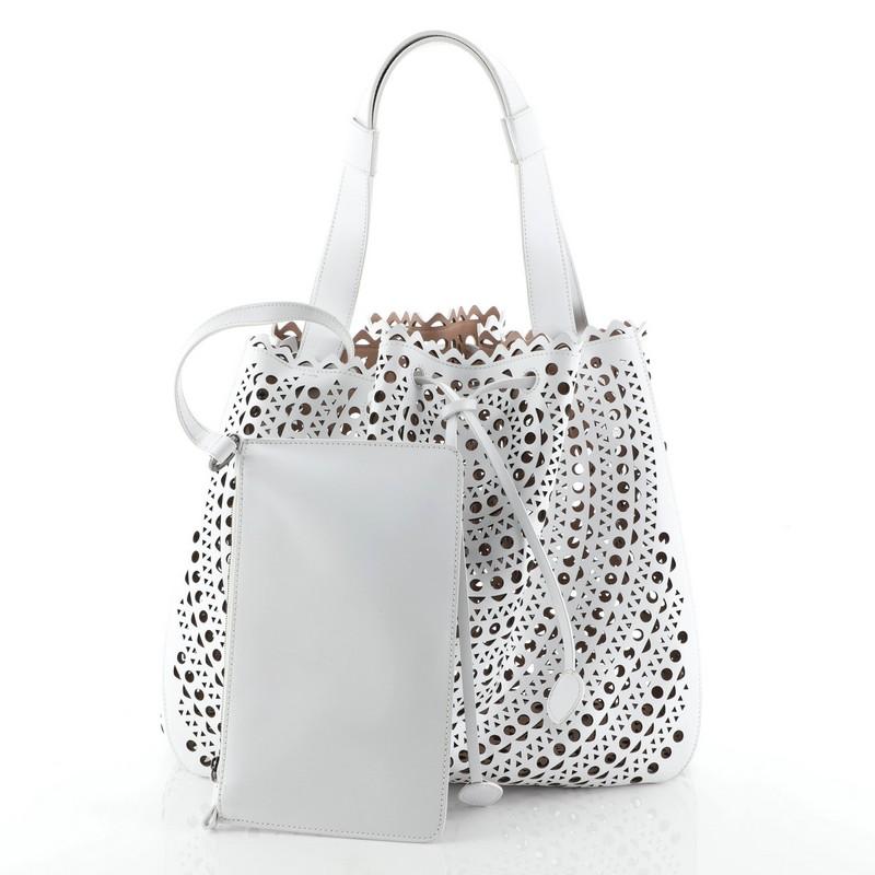 This Alaia Bucket Tote Laser Cut Leather, crafted in a white laser cut leather, features a leather handle, and gunmetal-tone hardware. Its drawstring closure opens to a neutral laser cut leather interior.

Condition: Very good. Loss of shape on