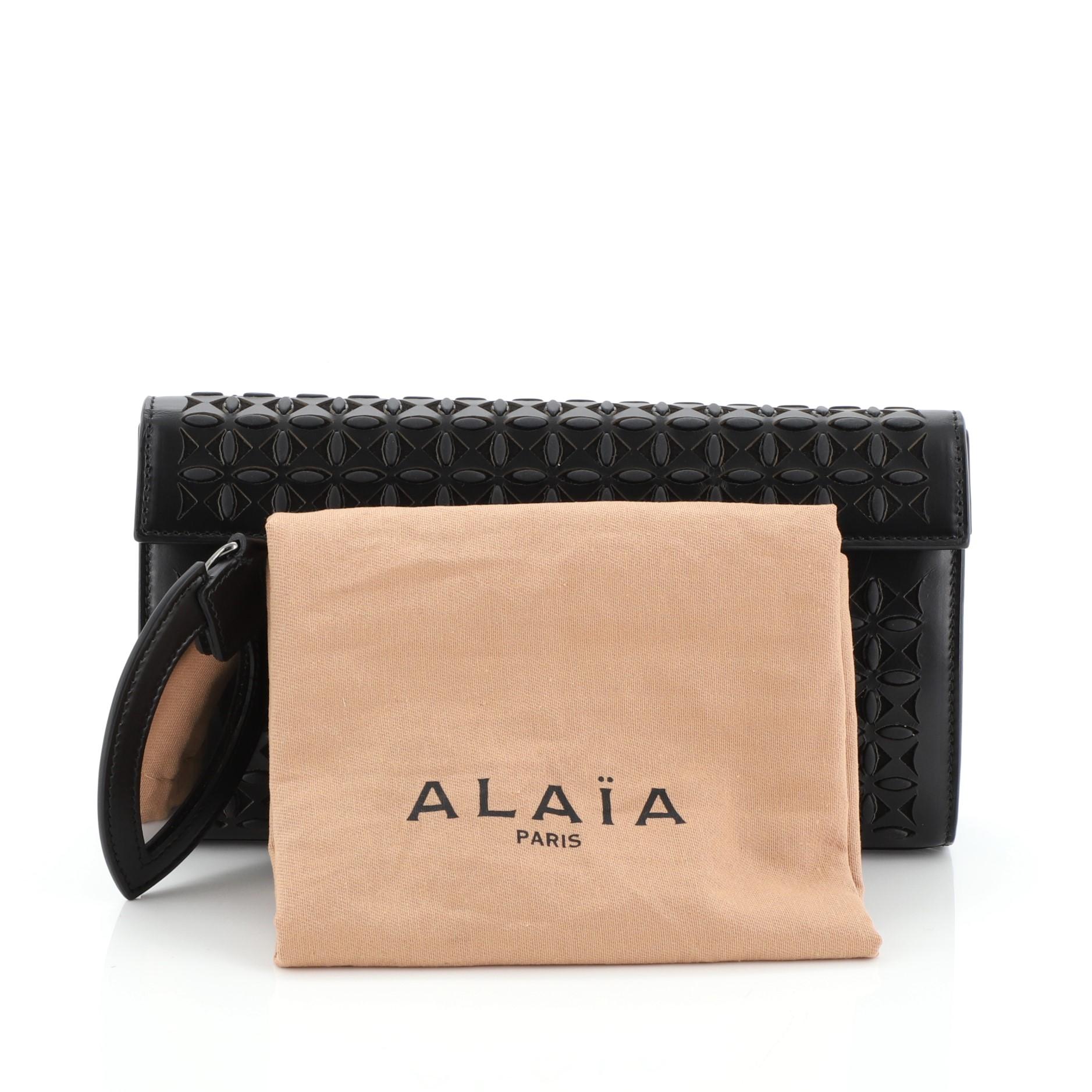 This Alaia Flap Clutch Laser Cut Leather Small, crafted in black laser-cut leather, features gunmetal-tone hardware. Its magnetic closure opens to a neutral leather interior with slip pocket.

Estimated Retail Price: $1,970
Condition: Very good.