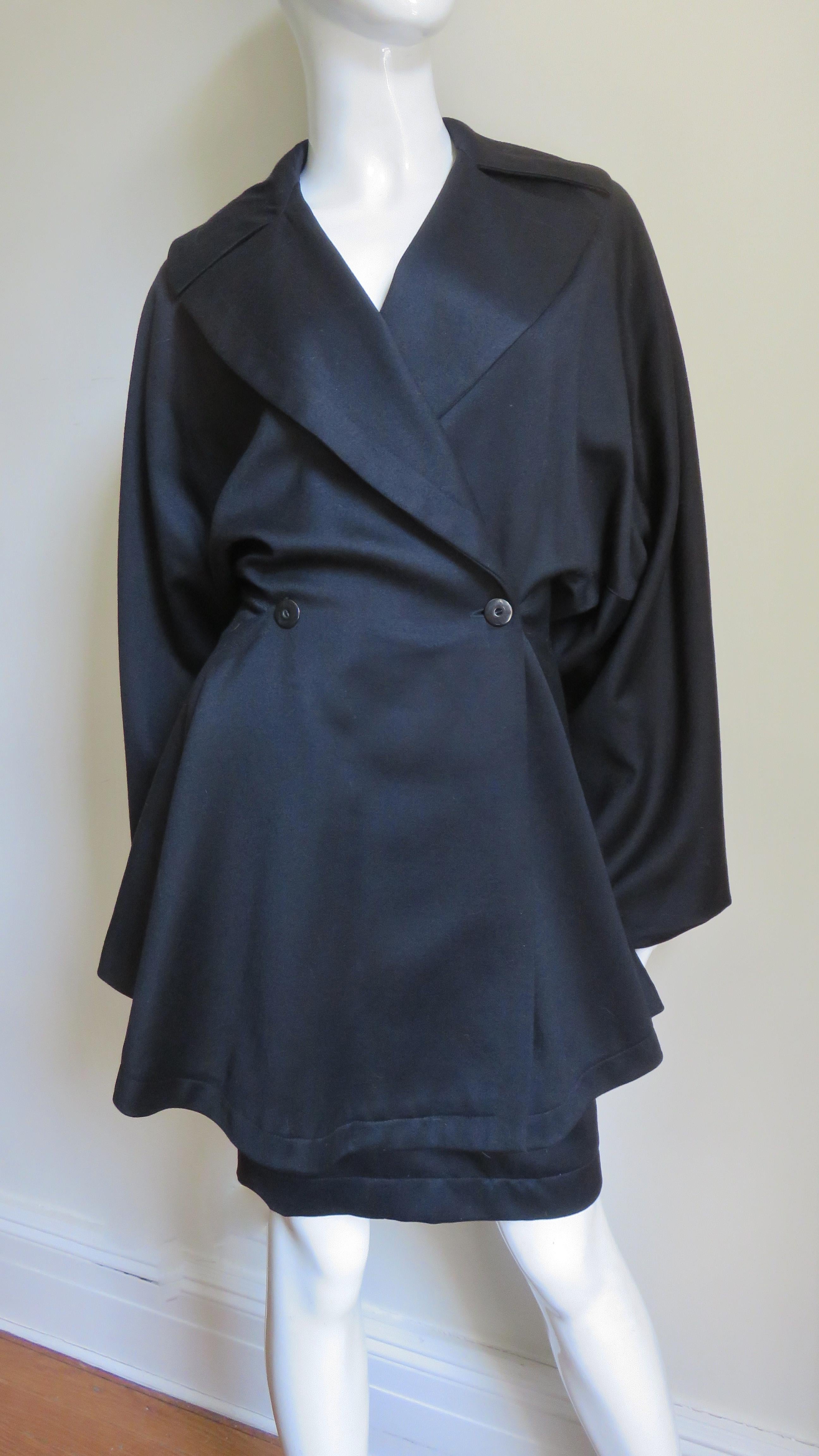 Une étonnante combinaison 3 pièces en laine noire d'Azzedine Alaia, composée d'une jupe, d'un pantalon et d'une veste, telle qu'elle est présentée dans le catalogue de la marque  Musée de la mode SCAD à Atlanta.  La veste spectaculaire qui s'enroule