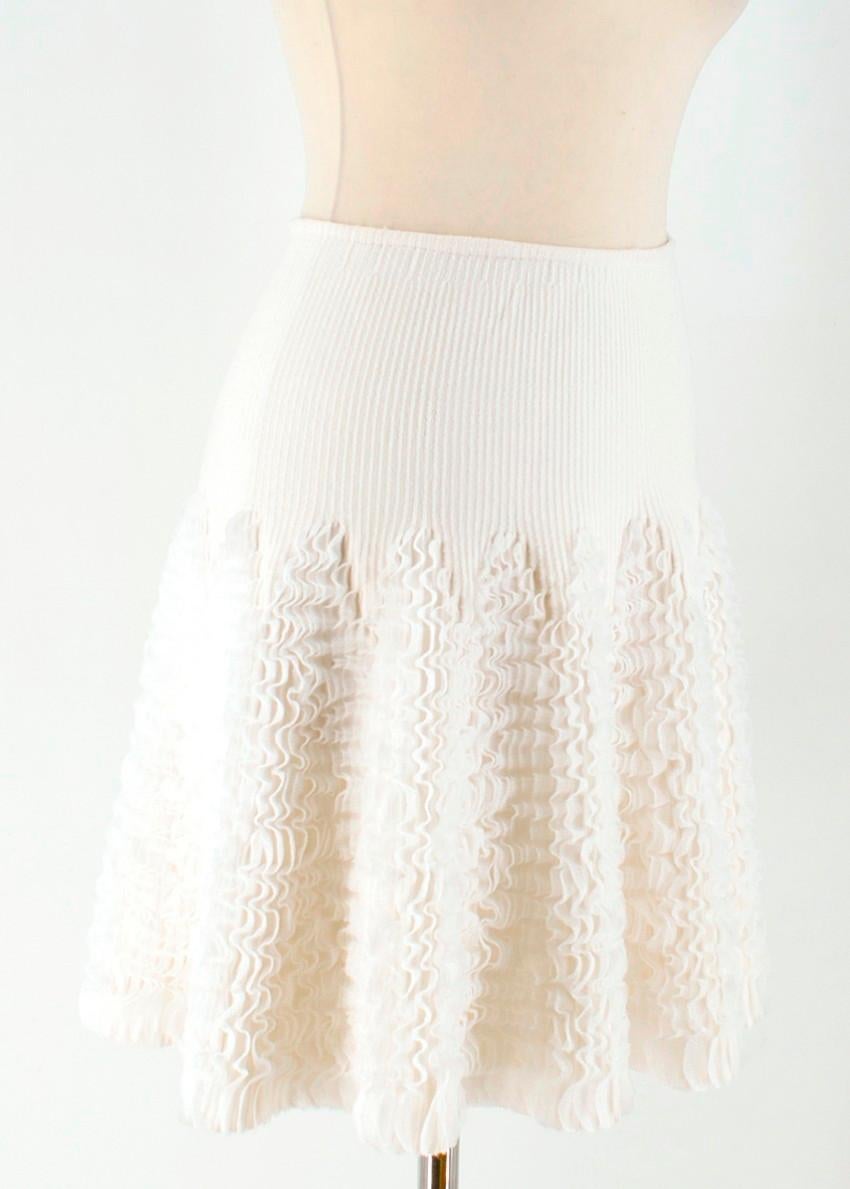 ALAÏA ivory ruffle-trimmed stretch-knit mini skirt

-	Ivory, heavyweight wool-blend knit 
-	Ruffle-trimmed godet inserts 
-	A-line mini skirt 
-	Centre-back concealed-zip fastening
-	66% Wool / 20% polyester / 12% nylon / 2% elastane

Please note,
