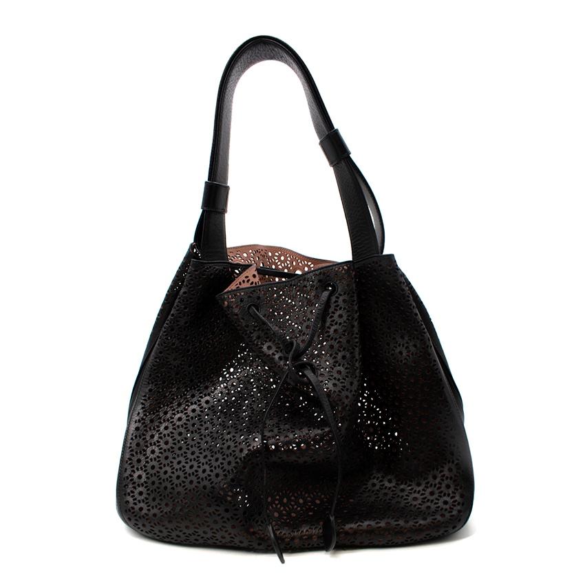 Alaia Medium Black Leather Laser Cut Tote Bag
 

 - Roomy leather tote, with signature Alaia laser cut work front and back
 - Geometric laser-cut circular patternation throughout 
 - Nude pink lining 
 - Detachable almond shape compact mirror, with