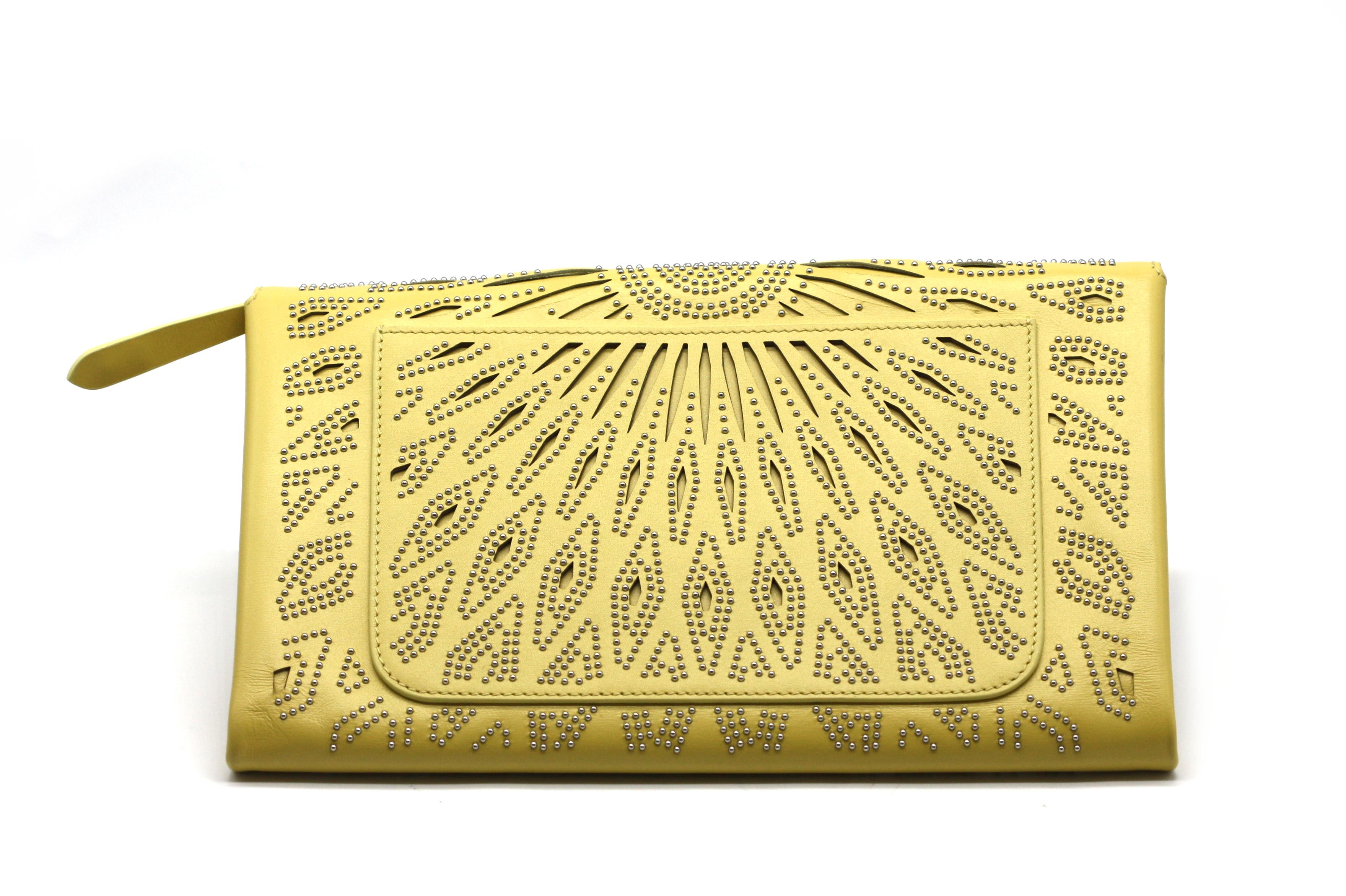 
Alaia Metal-Mounted Yellow Leather Clutch
The rectangular body with both cut-outs and metal studs positioned to createan overall diamond and bead pattern, the flap with a snap closure, and reverse open pocket, the tan lined leather interior with an