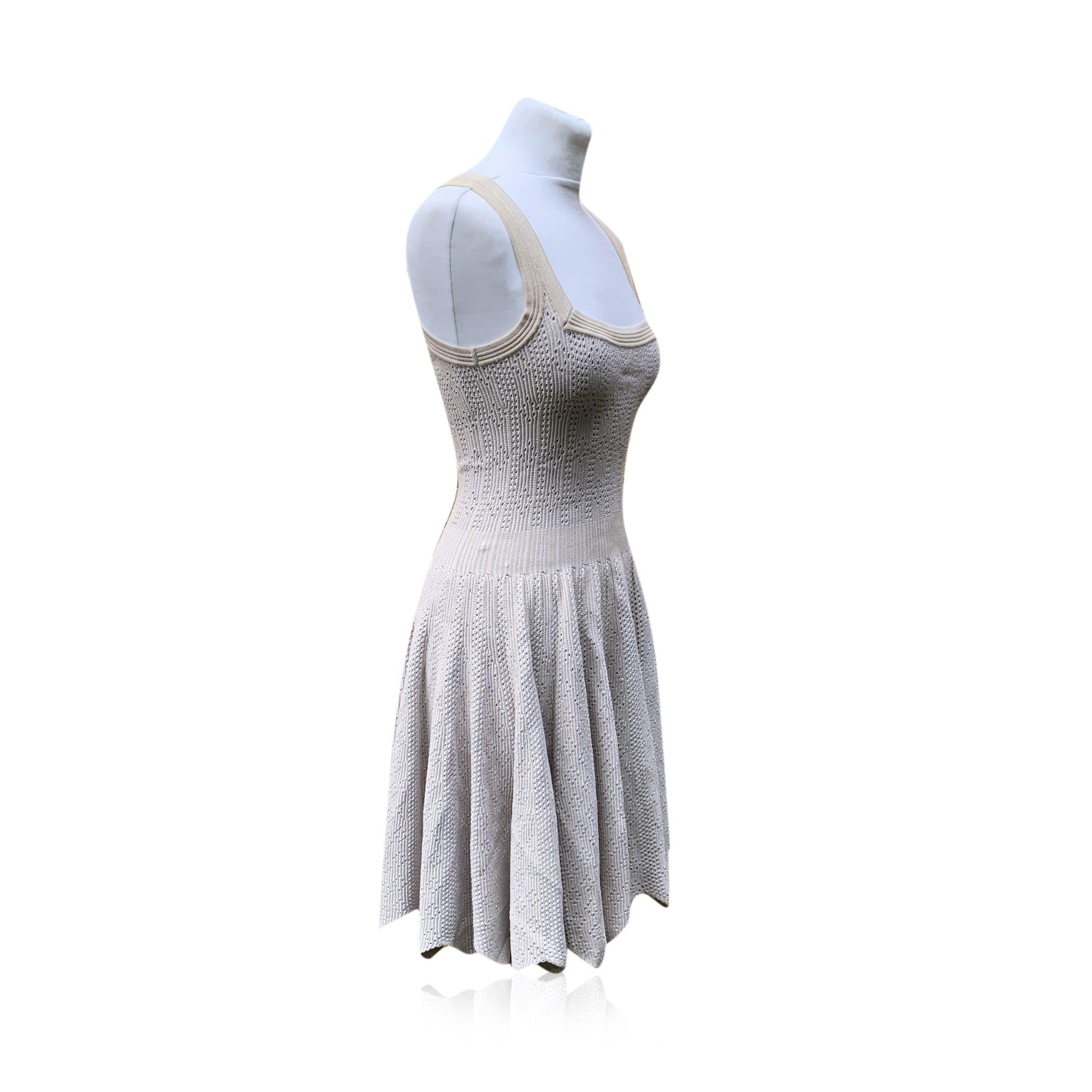 Beautiful knitted A-Line dress by Alaia, in beige color with a perforated style. Sleeveless design with square neckline and a zigzag hemline on the skirt. Unlined. Zip closure on the back. Composition: 85% Viscose, 10% Polyester , 5% Nylon. The