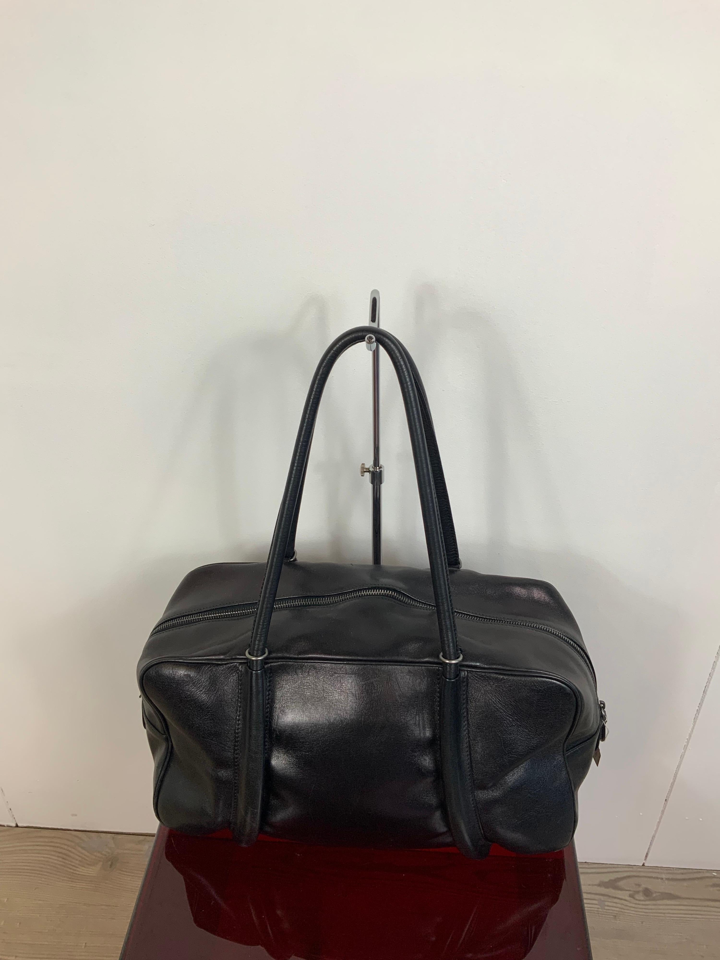 Alaia Paris bag.
Leather black leather. Pink interior. Silver hardware.
Zip closure. Inside of the bag you can find a small mirror as accessory.
Bag corners show some use of sign. 
Measurements:
height 21 cm
width 39 cm
depth 14 cm
handle 27