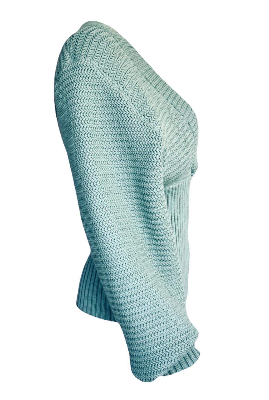 Issu de la collection automne 1986 d'Azzedine Alaïa, ce cardigan rare est un exemple frappant de la maîtrise du créateur en matière de tricots sculpturaux. Confectionné en maille de laine stretch turquoise, il présente un décolleté en V profond, des