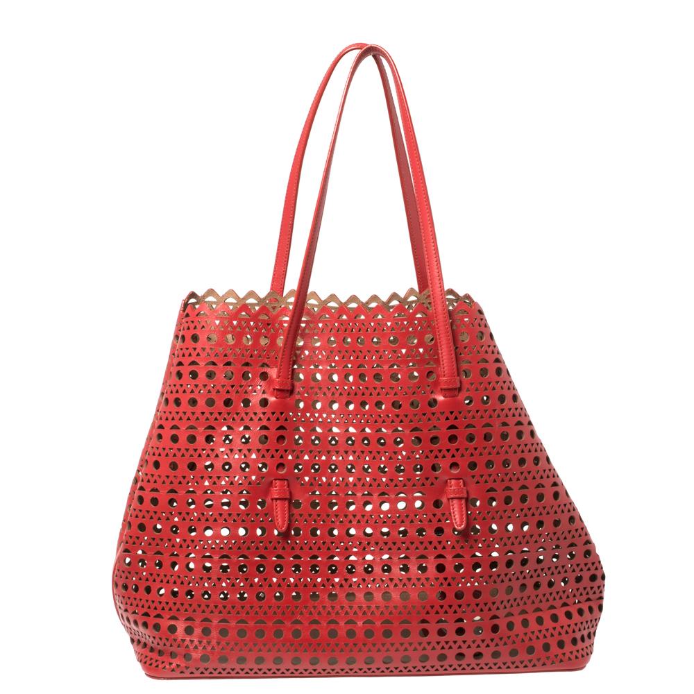 Stunning like no other, this Mina tote by Alaia is sure to make a stylish statement! The red creation is crafted from leather and features impressive cutouts adorning the exterior. It has an open-top that reveals a leather-lined interior with enough