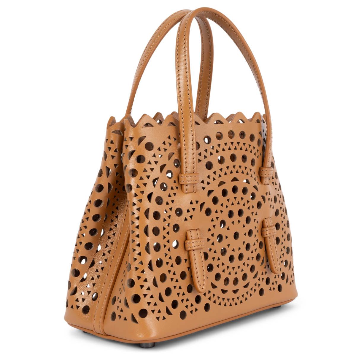 100% authentic Alaïa Mina 16 micro tote bag in tan brown Vienne Wave calfskin leather. The Vienne pattern is inspired by precious lace and moucharabieh architectural openwork. Features double handles, snap-fastening gusseted sides that expand and a