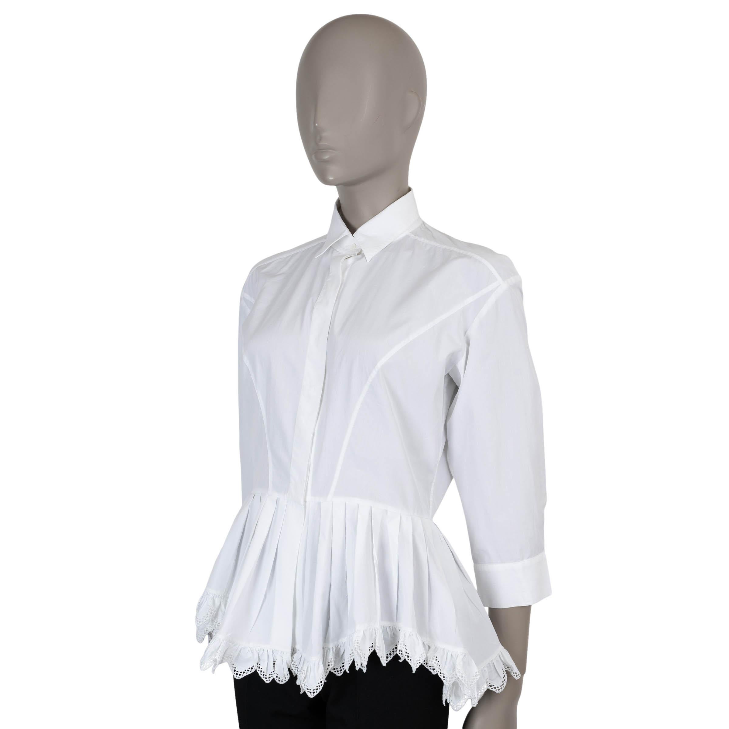 Questa camicia 100% autentica di Alaïa in popeline di cotone bianco (100%) è una raffinata espressione dell'eleganza scultorea della maison. Progettato con una silhouette aderente, presenta un peplo plissettato che esalta il punto vita, un colletto