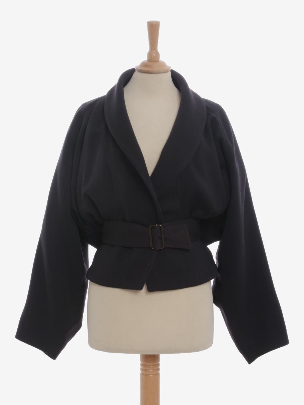 Alaïa Wool Belted Jacket is a rare blazer made by Azzedine Alaïa in the second half of 1980s with a shawl collar and slightly batwing sleeves. The crossover waistband is adjustable, and the sides are decorated with multi pence that create a balloon