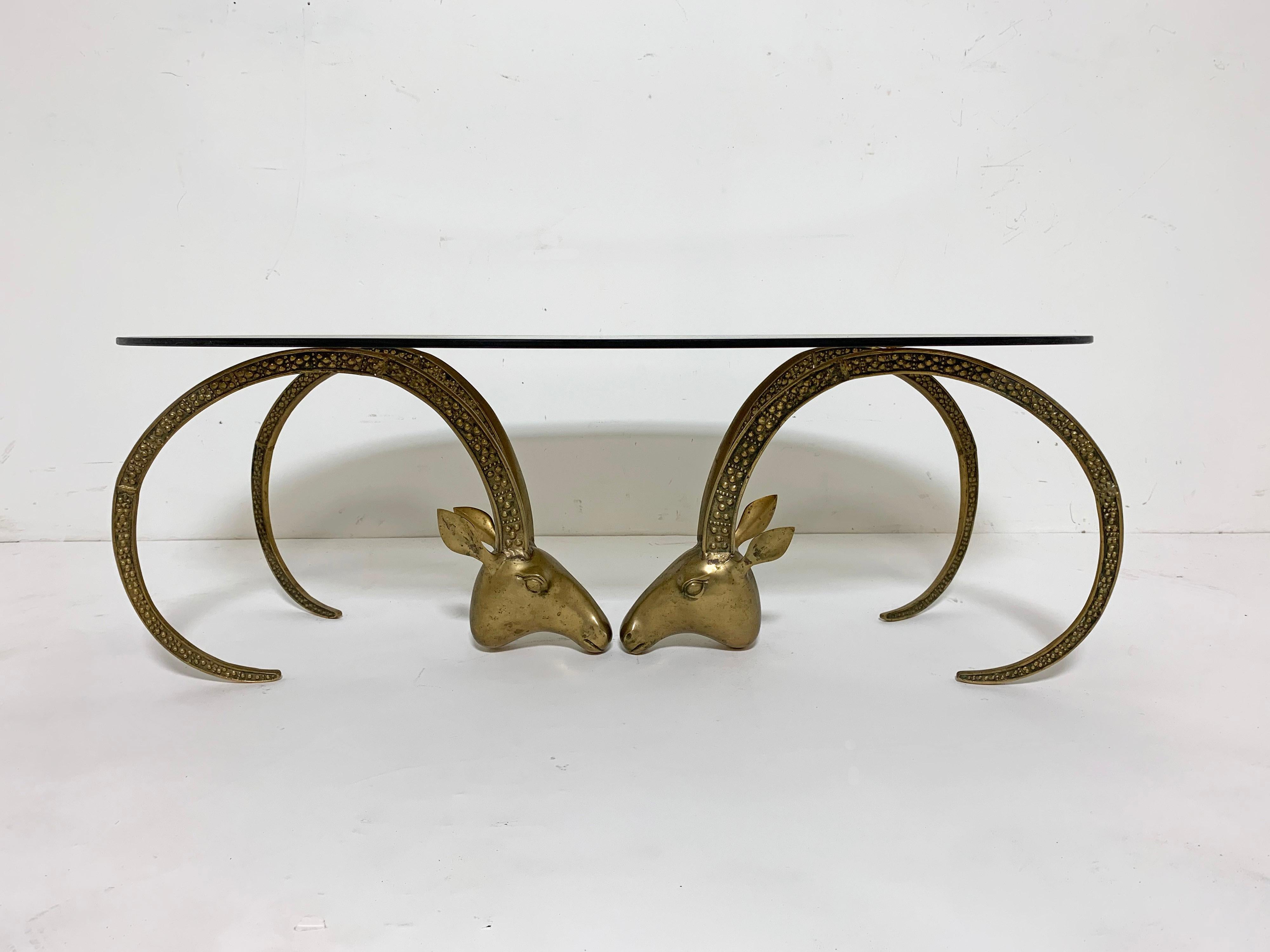 A 1970s coffee table, in the manner of the French sculptor and designer Alain Chervet, features a pair of bronze ibex heads with original smoked glass oval top.
