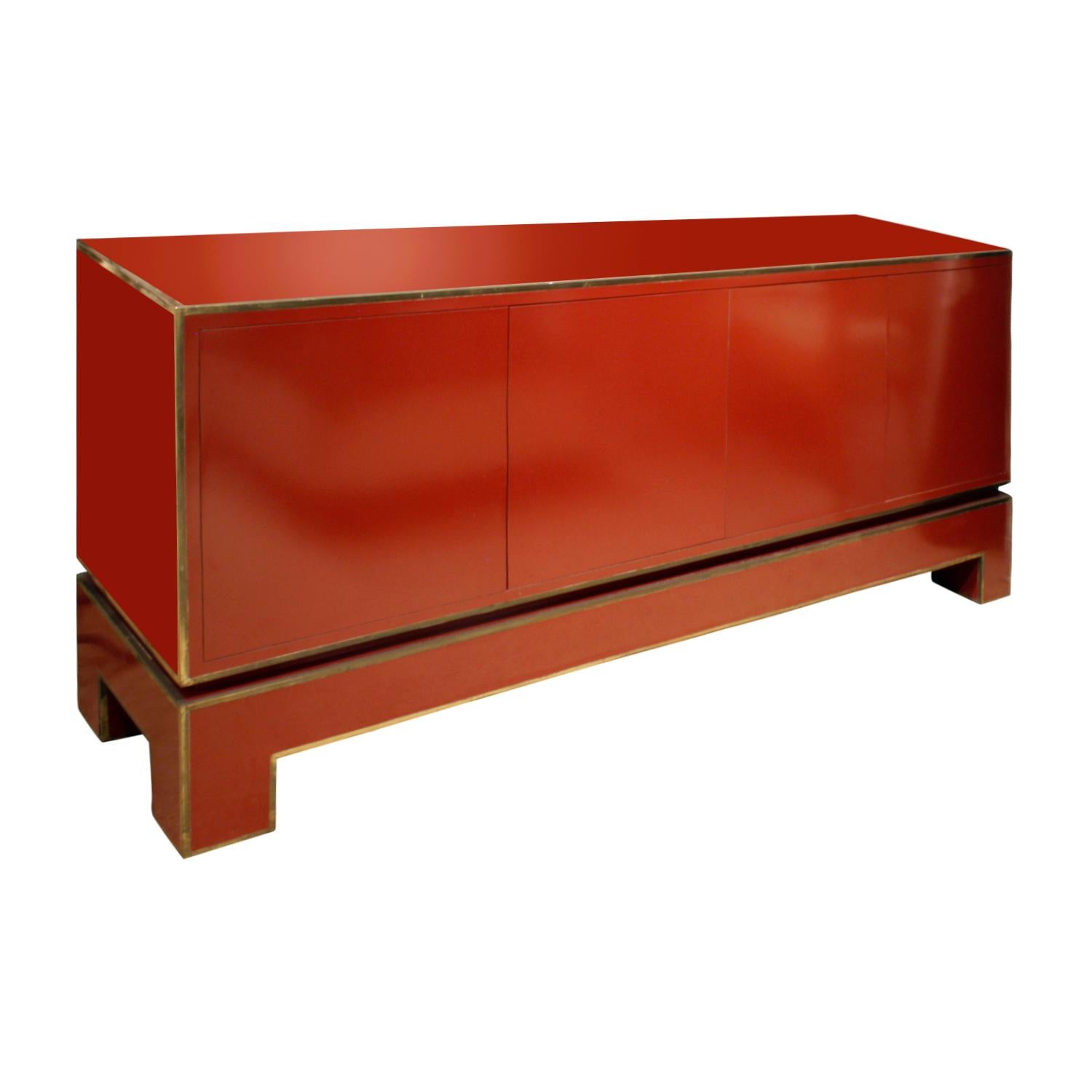 4-door credenza in red lacquer with brass trim by Alain Delon for Maison Jansen, France, 1970s. Signed “ADelon” on brass label on interior of far left door. There are glass shelves inside. This is a very chic credenza.