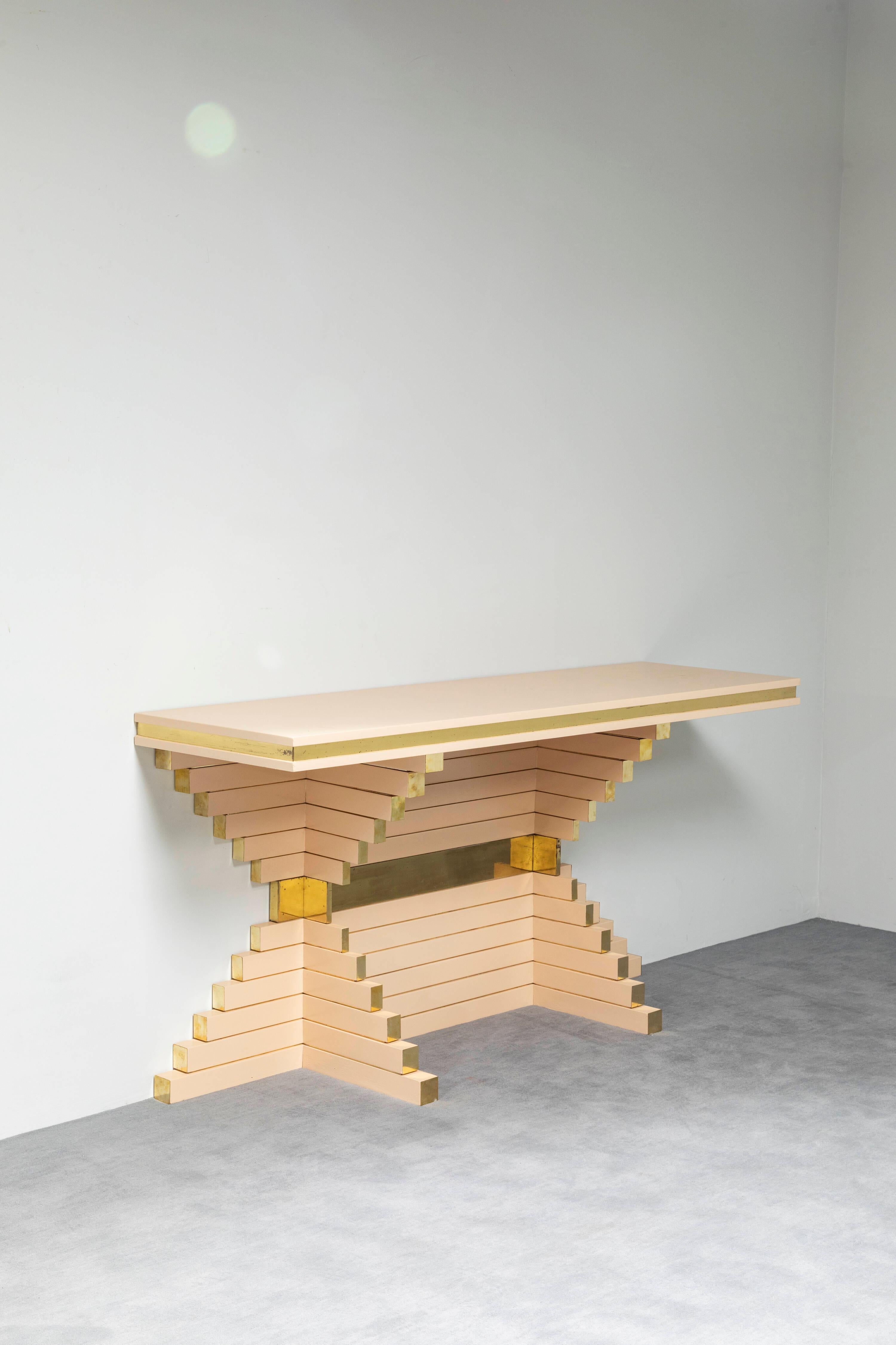 Table console unique en son genre, conçue par Alain Delon pour la Maison Jansen, elle présente une silhouette de gratte-ciel avec sa magnifique forme obtuse superposée. Cette console présente une finition laquée ivoire avec des bandes et des