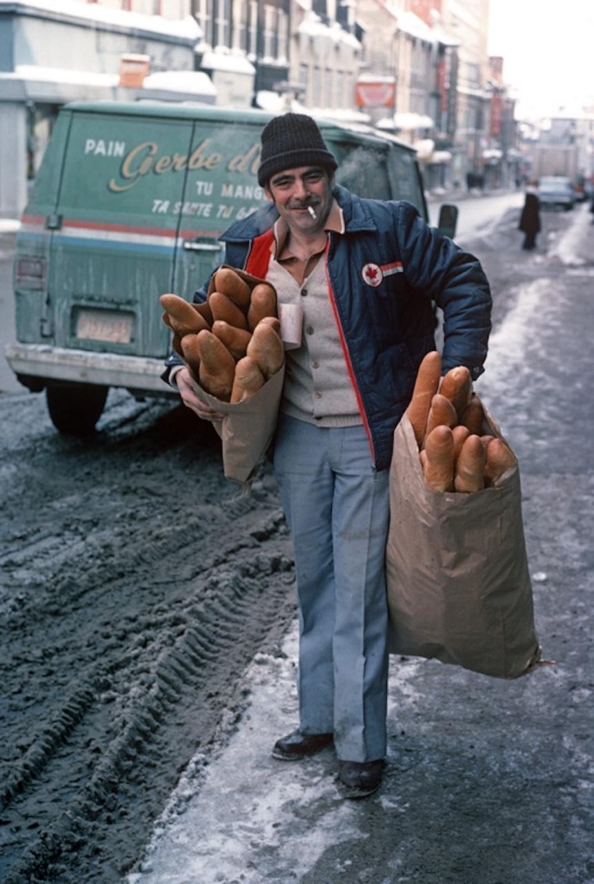 Daily Bread by Alain Le Garsmeur
A bread delivery man with bags filled with baguettes on a snowy street in Quebec Province, Canada, 1977.

Paper size 24 x 20 inches / 60 x 50 cm
Printed in 2022 - produced from the original transparency
Archival