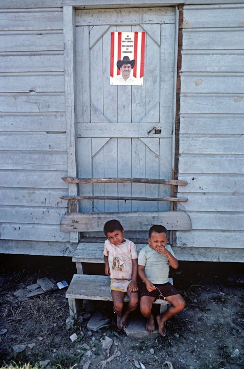 Verandastufen von Alain Le Garsmeur
Zwei kleine Kinder sitzen vor den Häusern der Bananenplantagenarbeiter, Bananenplantage Isletas, Honduras, Mittelamerika, 1981. 

Papierformat 20 x 16 Zoll / 50 x 40 cm
Gedruckt im Jahr 2022 - hergestellt von der