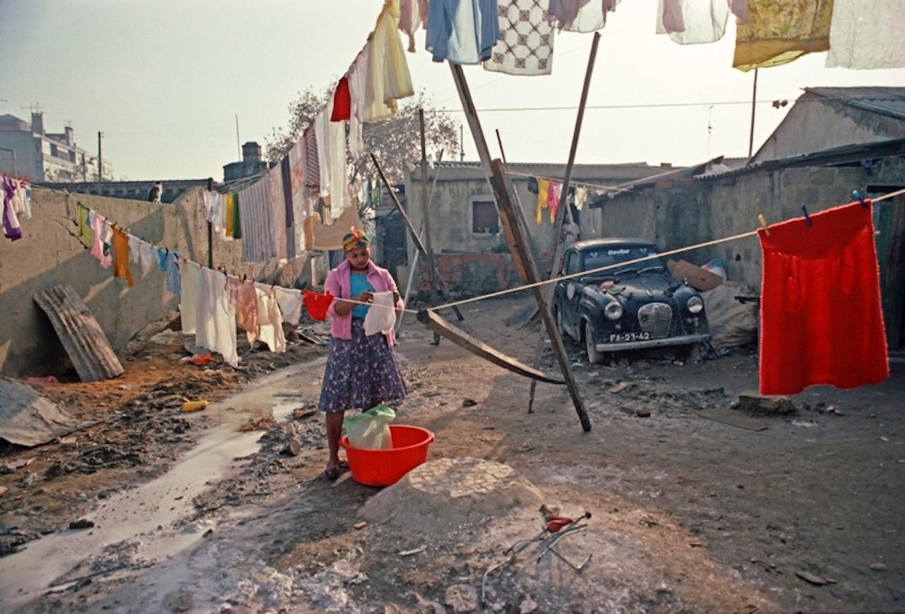 Washing Line von Alain Le Garsmeur
Eine Einwanderin aus Kap Verde hängt die Wäsche auf, Lissabon, Portugal, 1984.

Papierformat 16 x 20 Zoll / 40 x 50 cm 
Gedruckt im Jahr 2022 - hergestellt von der Originalfolie
Archival Pigment Print und