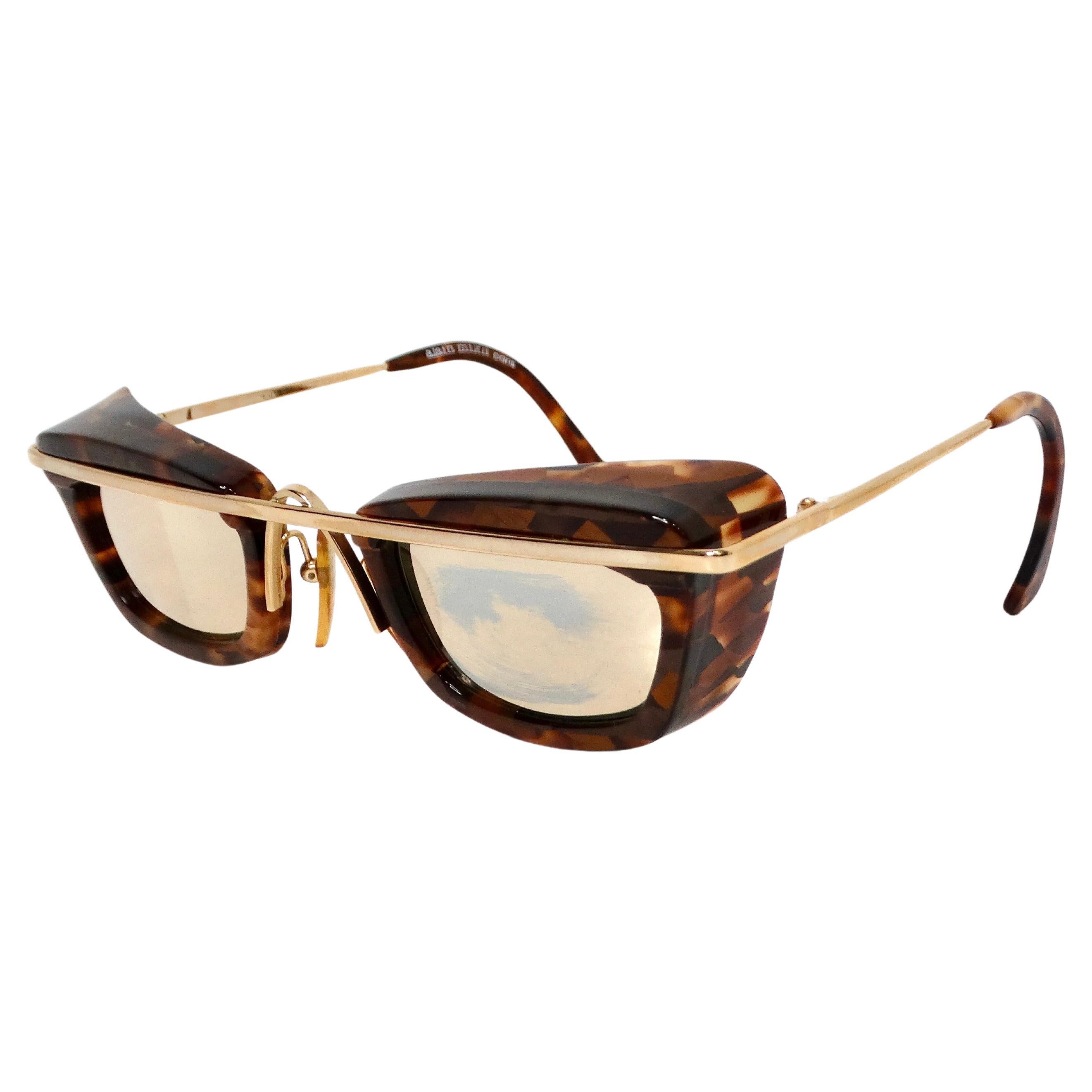 Les lunettes de soleil Alain Mikli, datant des années 1990, sont un mélange frappant de sophistication vintage et de mode audacieuse. Elles sont dotées d'un verre toréo et d'un verre miroité en or. Les montures sont fabriquées dans un motif