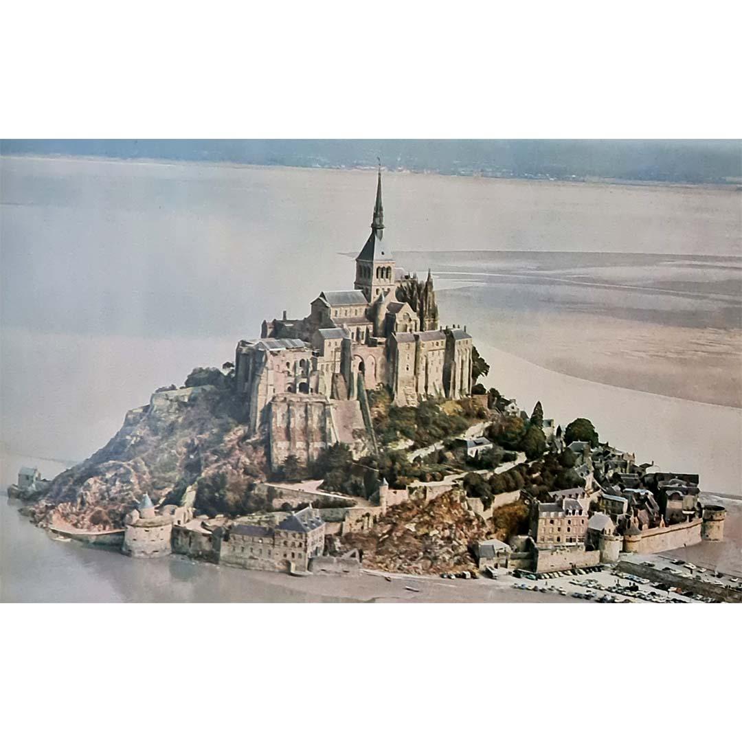 Cette affiche de voyage vintage de 1963, photographiée par Michele, capture magnifiquement la majesté et la solitude du Mont Saint-Michel, l'un des sites les plus précieux de France. Nichée en Normandie, dans la Manche, cette abbaye légendaire est