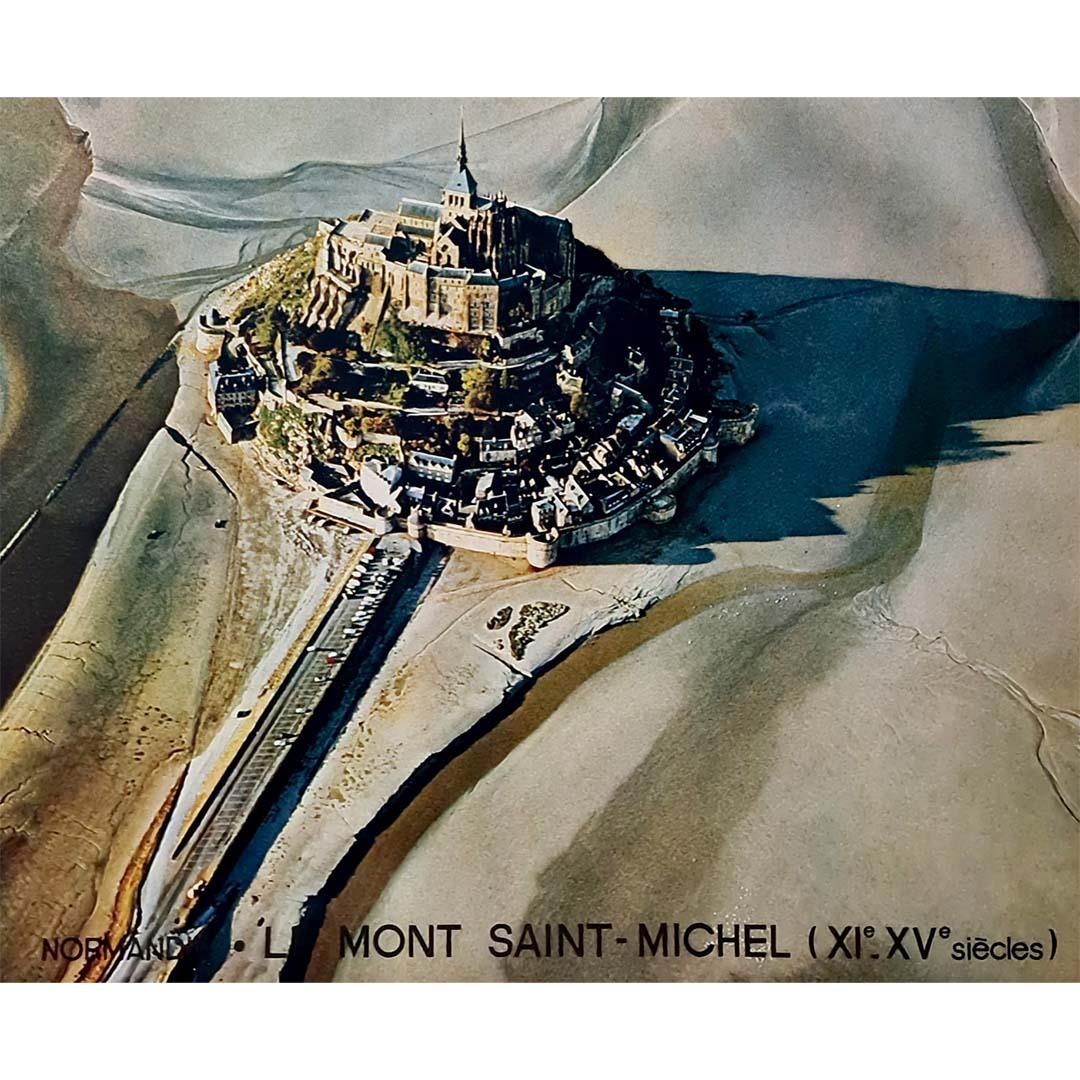 This 1972 original vintage poster by photographer Perceval captures the breathtaking beauty of Le Mont Saint-Michel, one of France’s most iconic landmarks. Nestled in Normandy, this medieval abbey, built between the 12th and 15th centuries, rises