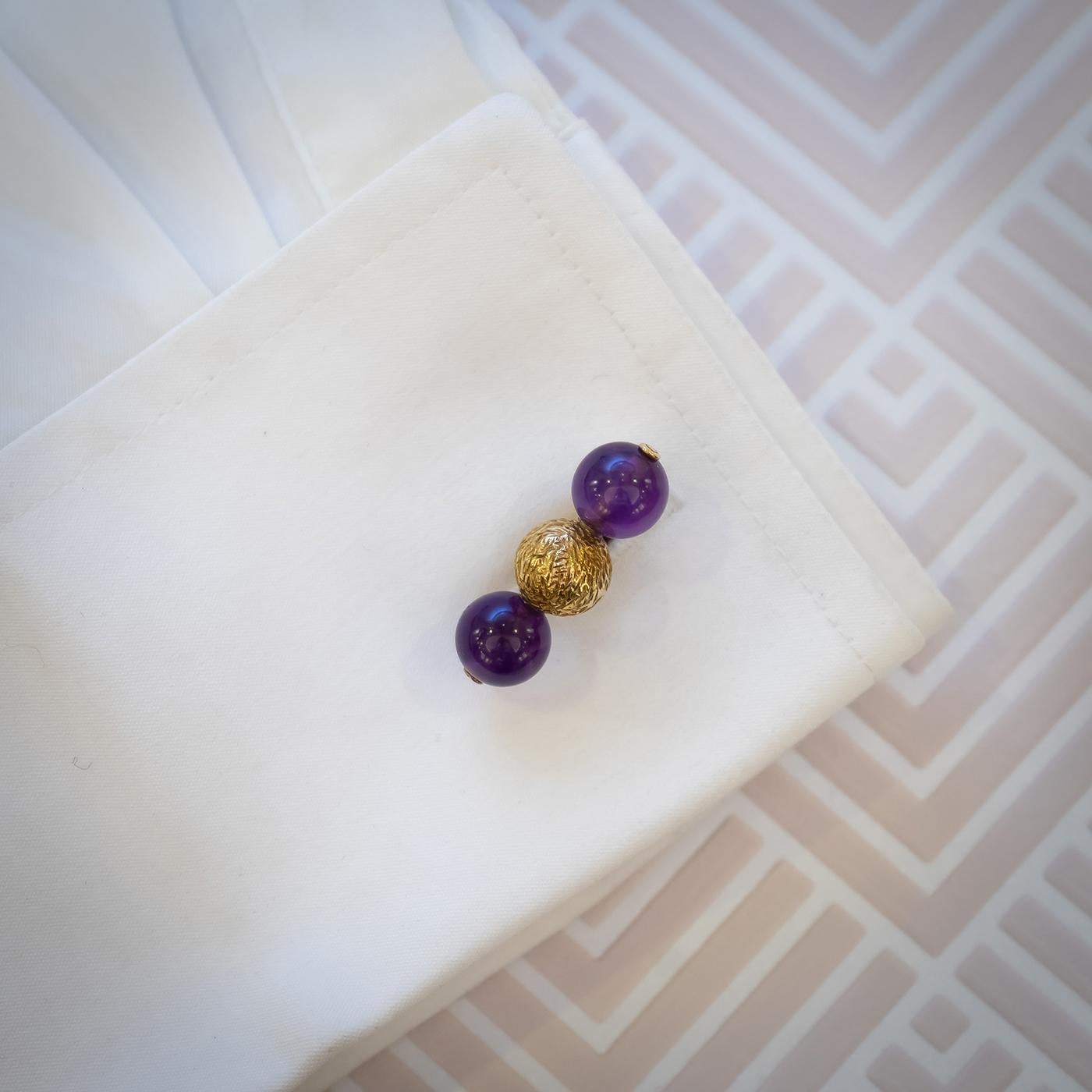 A pair of Alan Martin Gard amethyst and gold cufflinks, with figured gold balls in the centre and amethyst beads either side, with bar fittings, Hallmarked for London, 18ct gold, 1969, with AMG maker's mark. 

Alan Gard was born in London, in