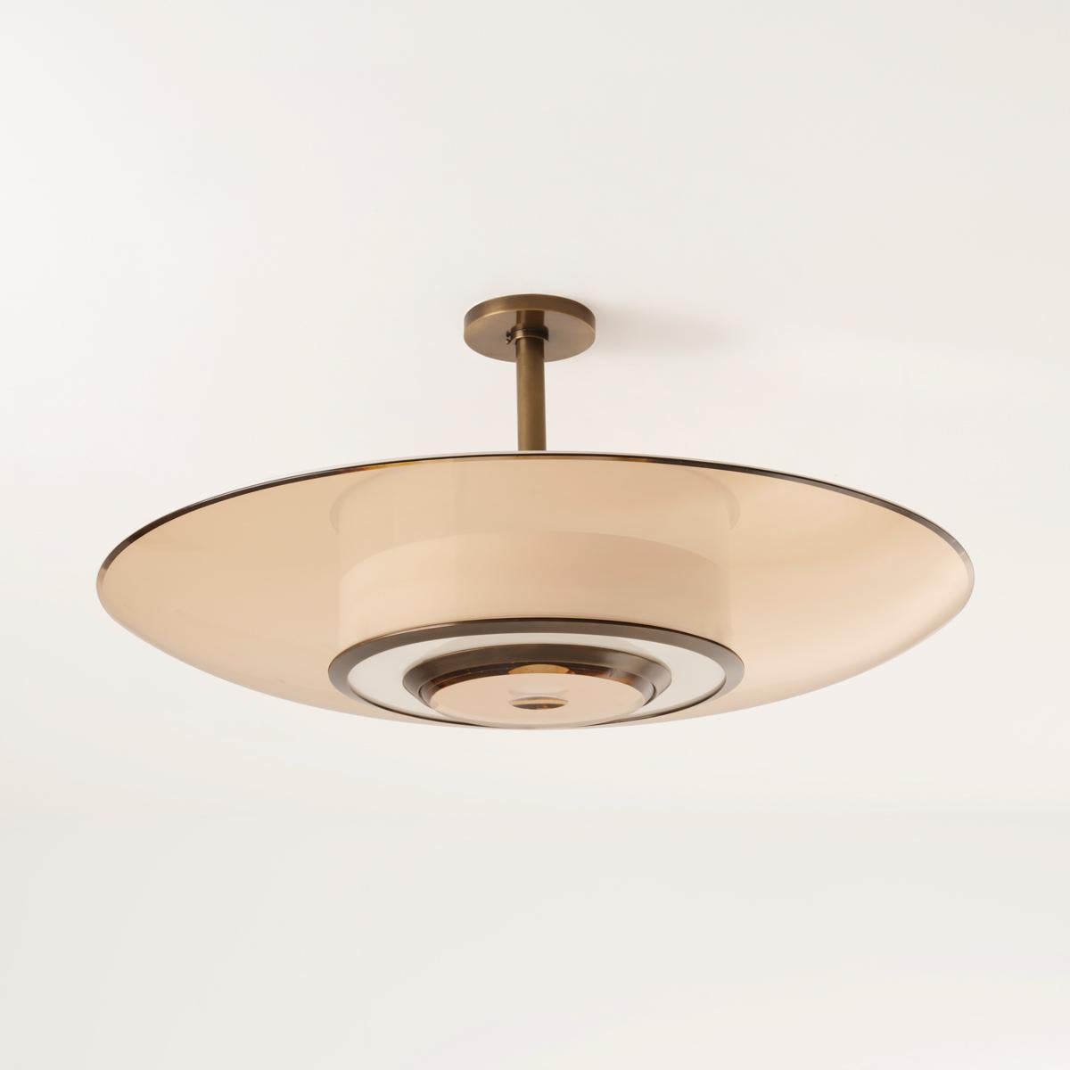 Le plafonnier Alba, inspiré par un chaud lever de soleil méditerranéen, joue avec les concepts de translucidité et de transparence. Cette pièce alterne le verre clair ou teinté et l'acrylique translucide, créant un motif équilibré par l'alternance