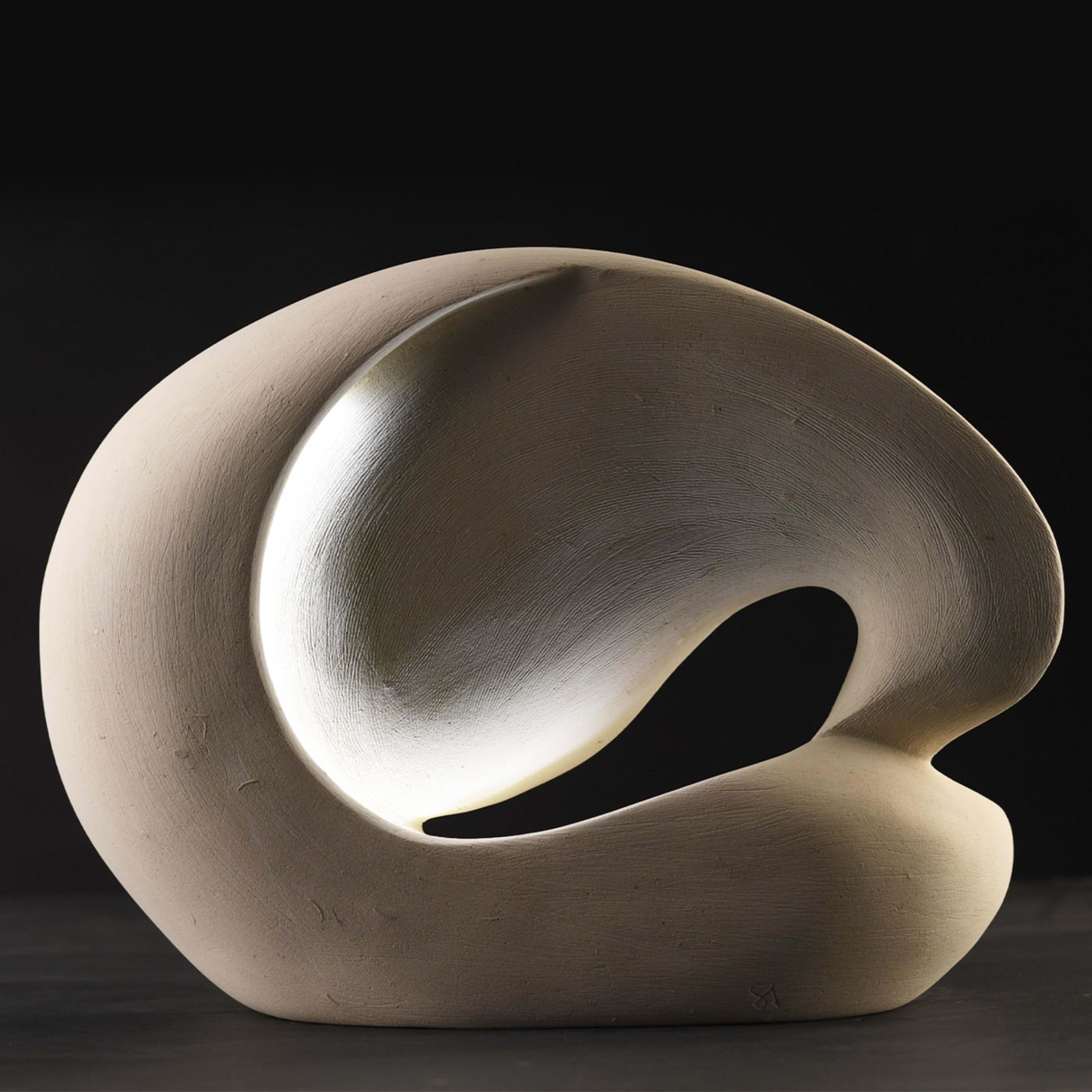 Artist Andrea Serra handcrafted this singular luminous sculpture with the delicate beauty of dawn light in mind. Its sinuous silhouette is fashioned of a special marine-origin stone, naturally bright and rich in fossils, that can only be quarried in