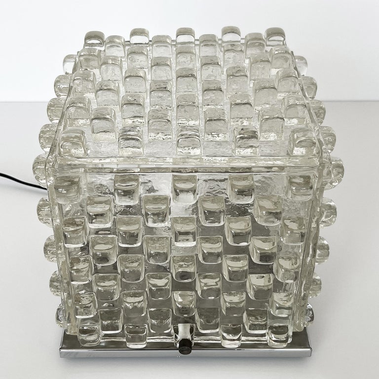 Sculptural glass cube table lamp by Albano Poli for Poliarte, circa 1970s. Cast clear Murano ice glass with a graphic geometric grid design of raised square protrusions. Chrome plated steel base. Brass hardware and recessed ball feel under chrome