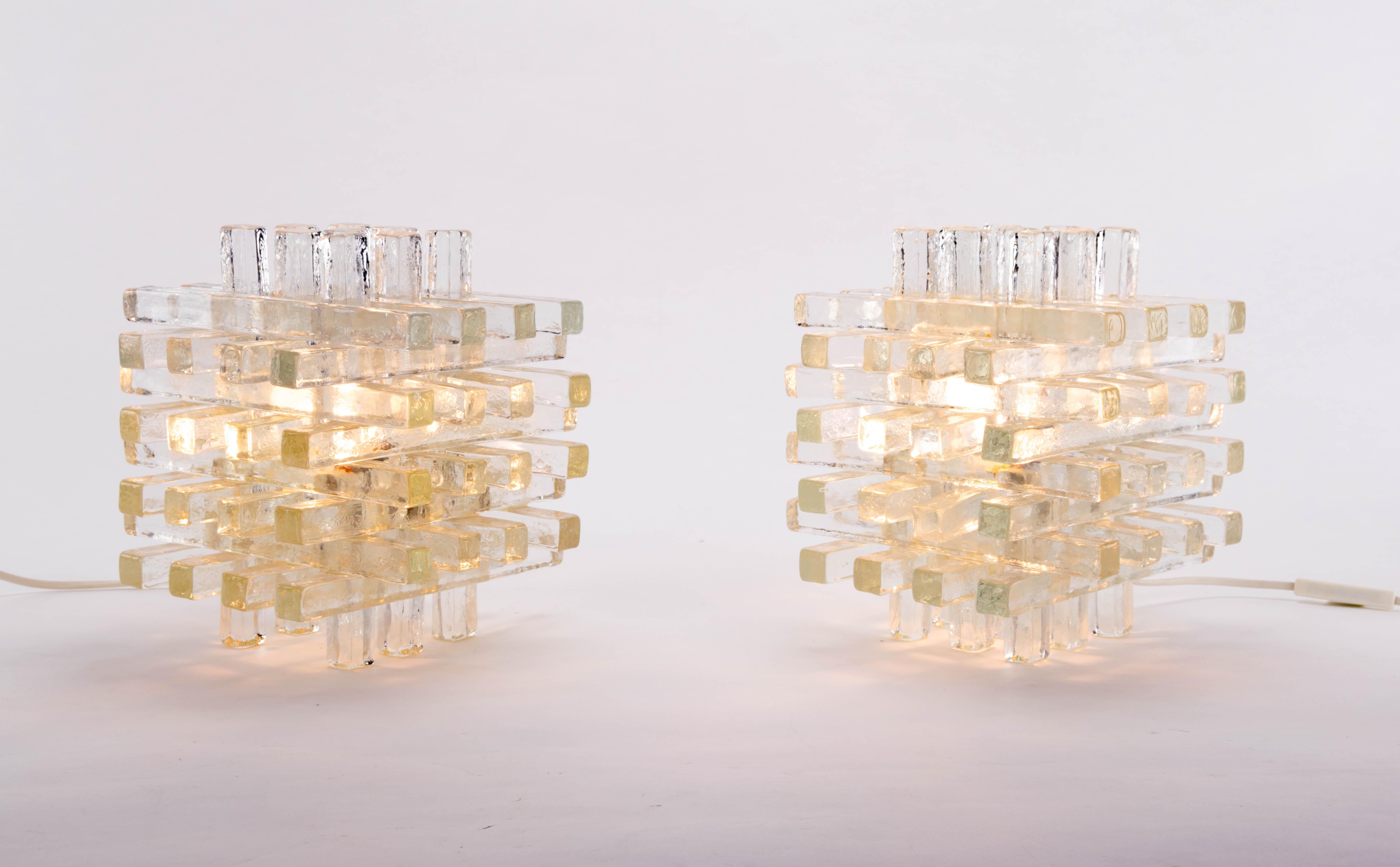 Set of two table lamps designed by Albano Poli for Poliarte Italia in the 1968. Made of hand blown Murano glass. Cubic shape consisting of glass segments with interwoven rectangular reliefs. When illuminated, the piece casts a warm golden glow and