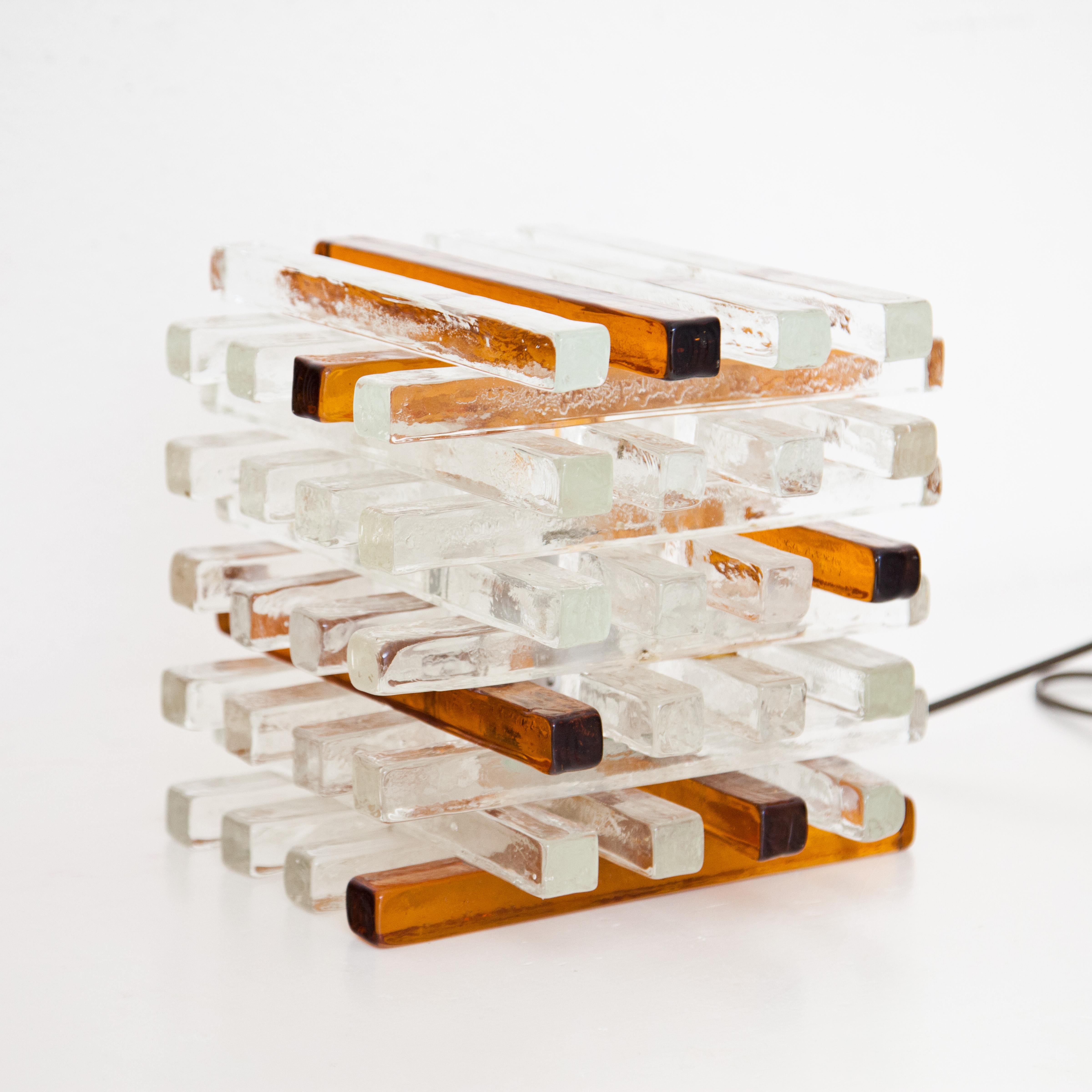 Table lamp consisting of rough glass rods stacked crosswise in alternating transparent and amber colours. Designed by Albano Poli for Poliarte. For the electrification we assume no liability and no warranty.