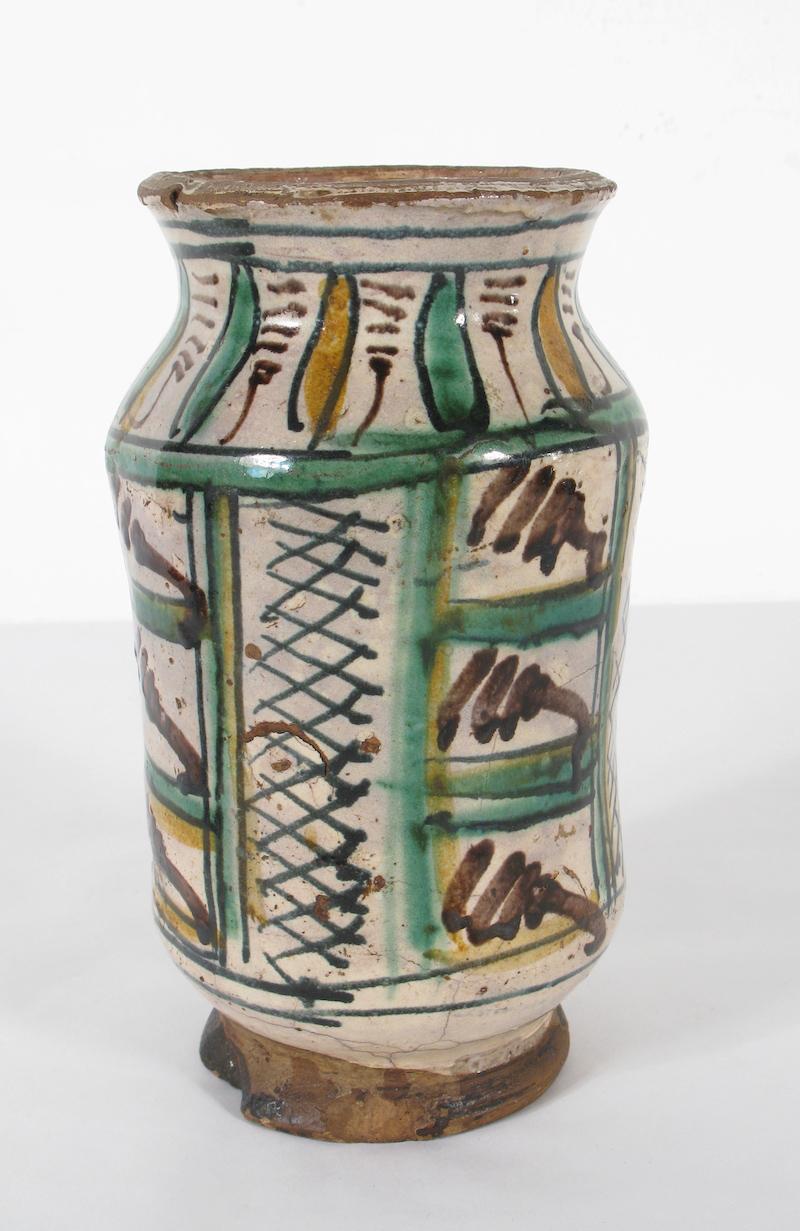 Polychrome archaic majolica albarello, central Italy, 15th century 

Cylindrical body with wide upper mouth with everted rim, concave neck, and foot with flat base.
Medium porous and orange/dark-brown/chamo ceramic body impasto
Ornamentation with