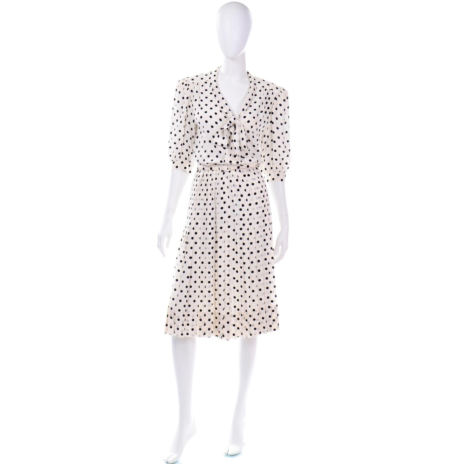 We love vintage Albert Nipon dresses and this 100% silk ivory and black polka dot dress is such an easy one to wear! The dress has a blousy top with gathered puff sleeves with buttons at cuffs. The flat pleated skirt is fitted through hip area then